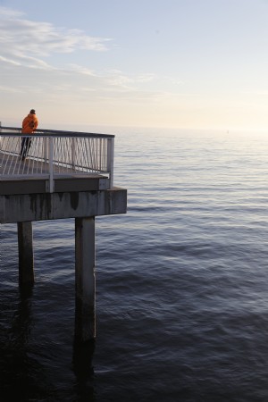 孤独な男は日没の写真で桟橋に立っています