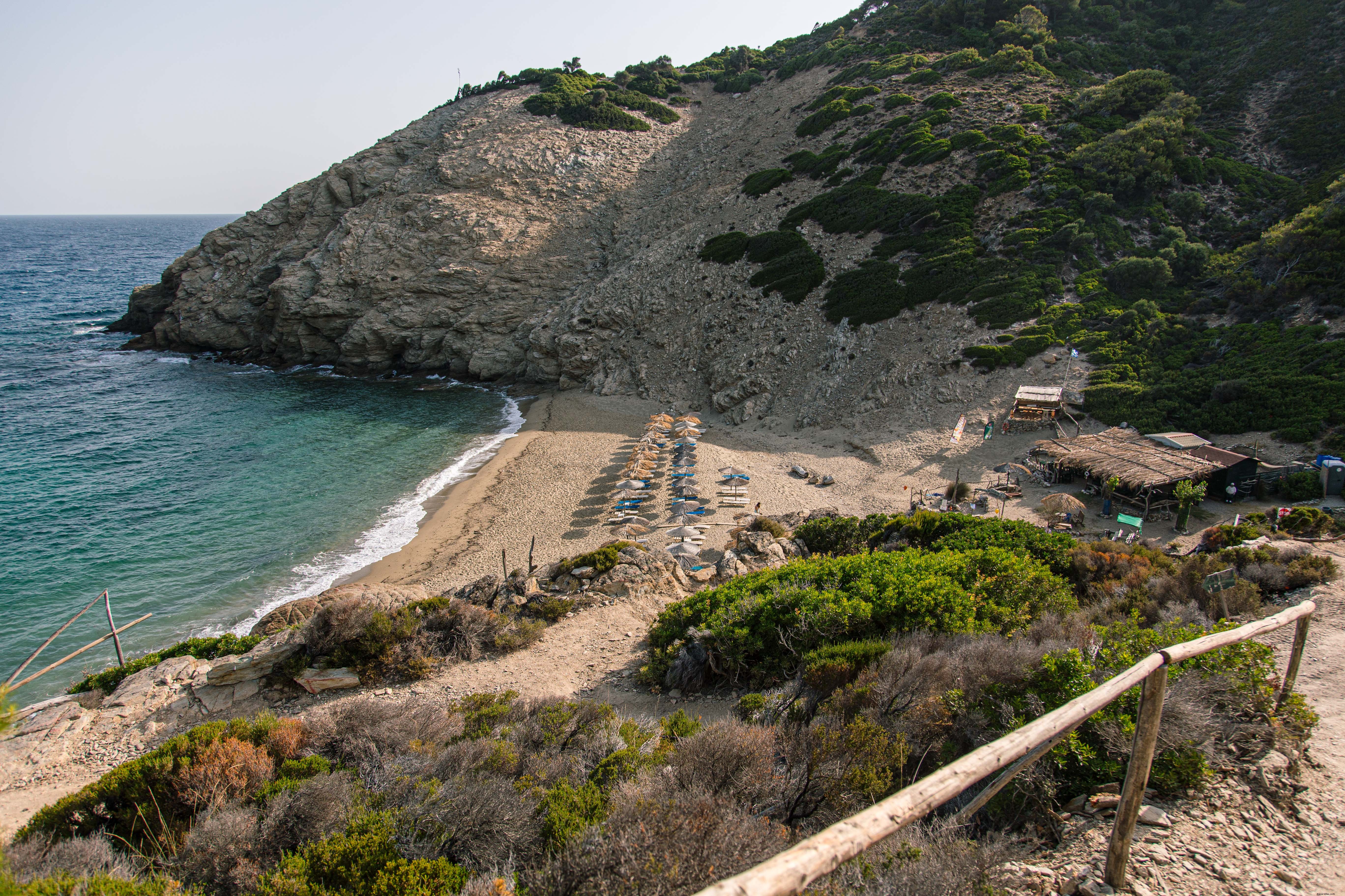 Foto de guarda-sóis de palha em uma praia na Grécia