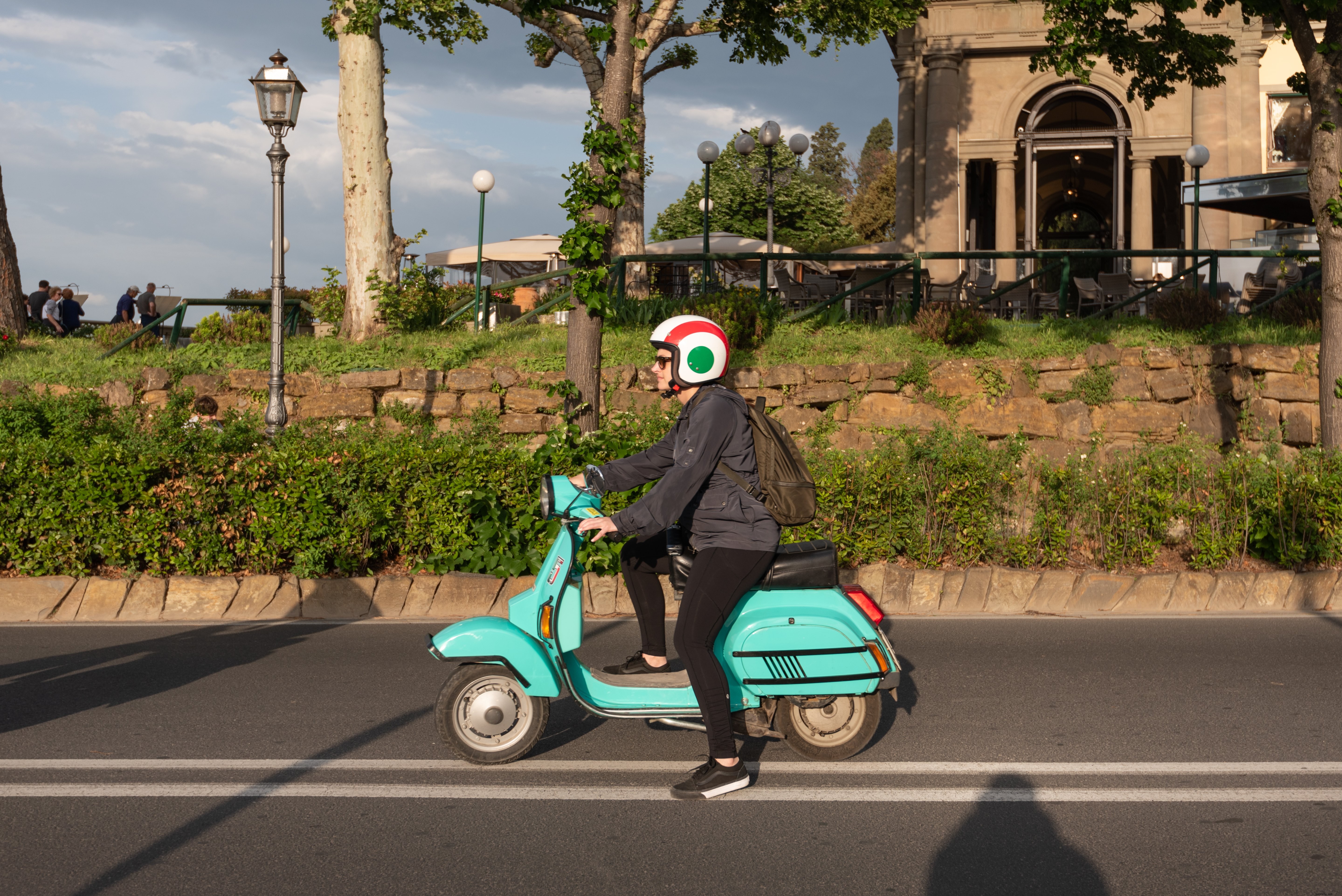 Una mujer en un ciclomotor turquesa en una carretera Foto