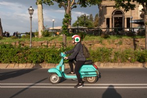 Una mujer en un ciclomotor turquesa en una carretera Foto