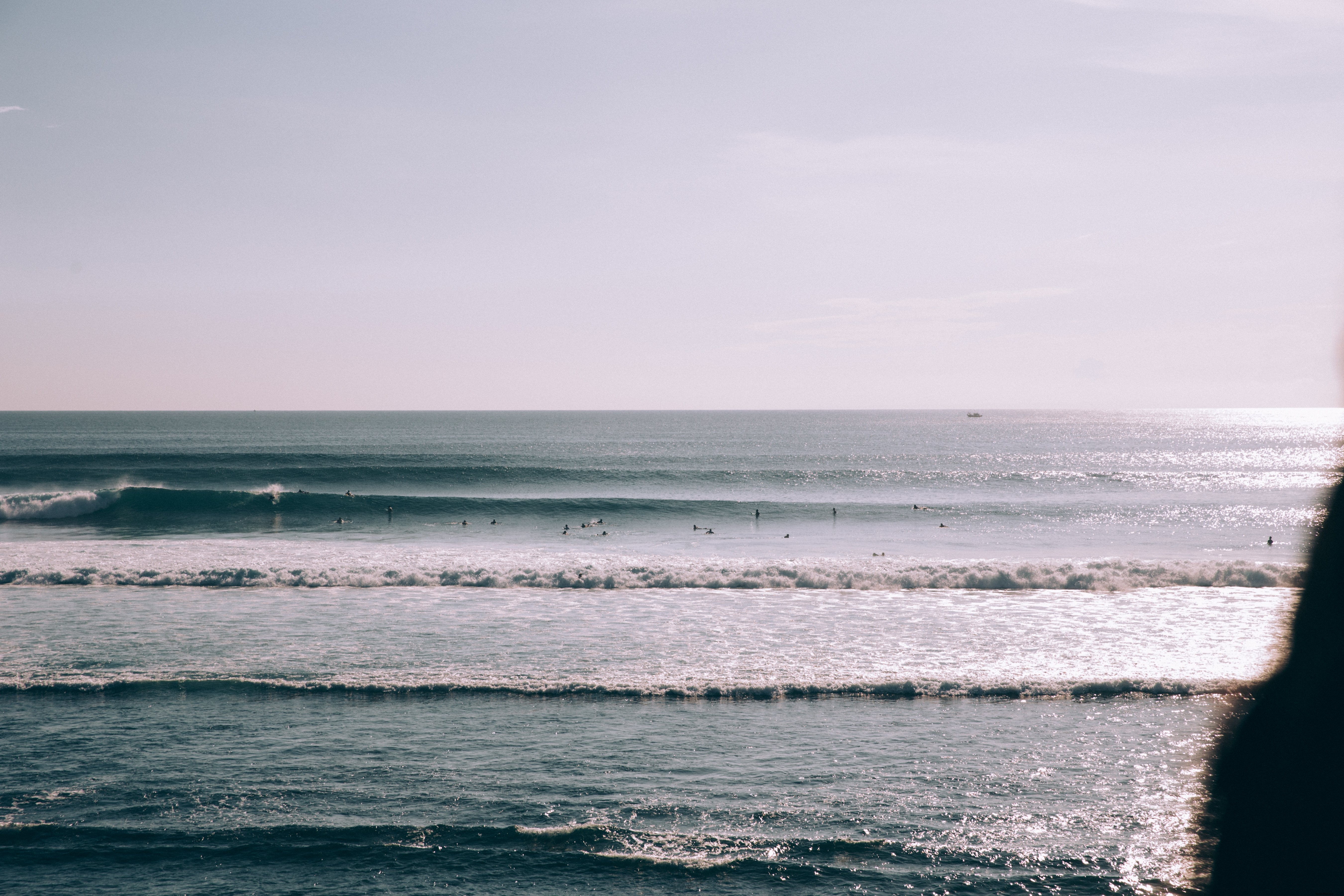 穏やかな波に沿って散らばっているスイマーとサーファー写真