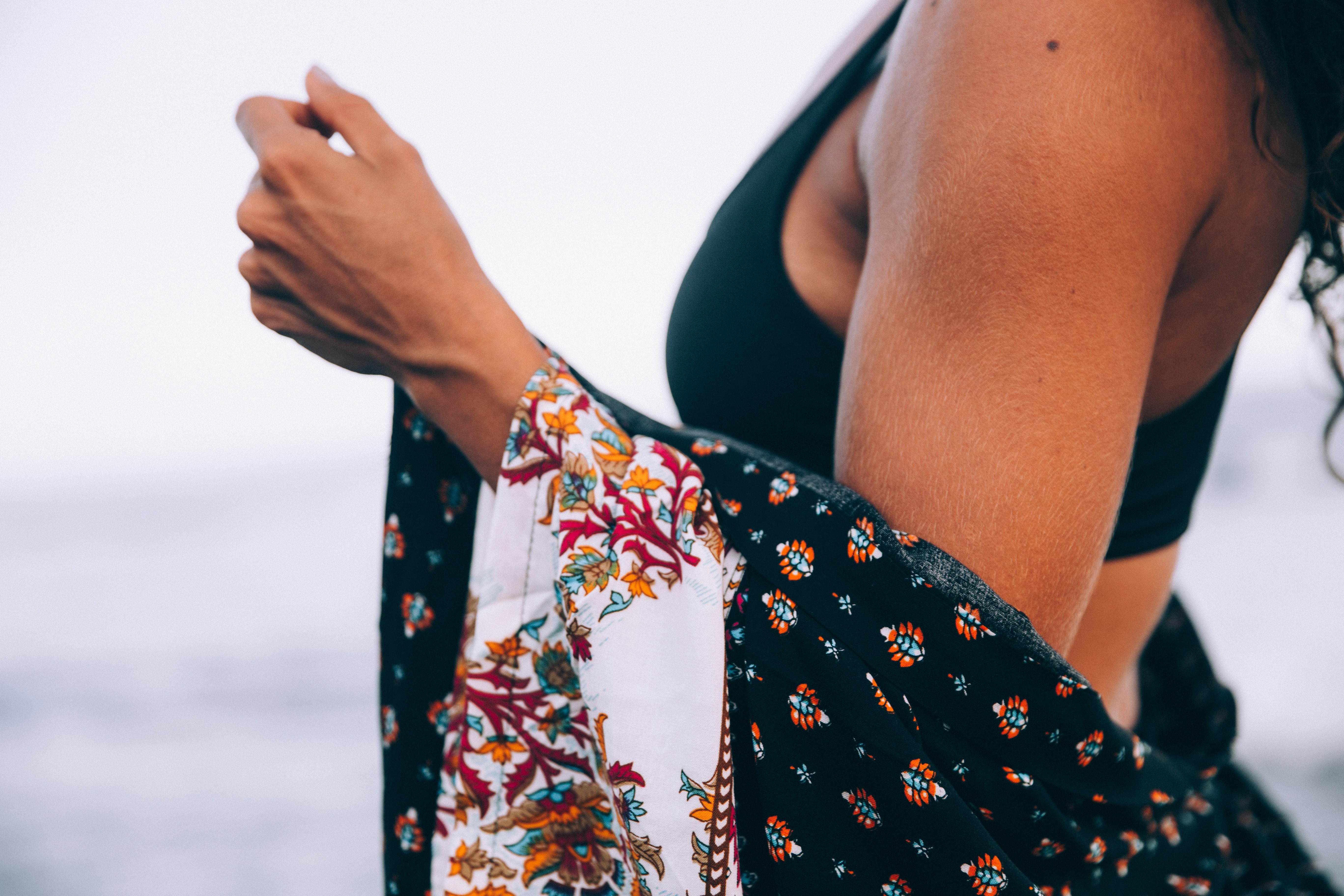 Uma mulher na praia com um xale estampado em volta dos ombros.