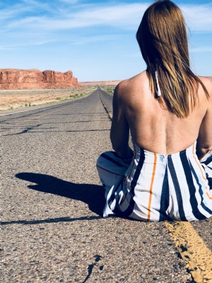 Uma mulher sentada no meio de uma rodovia no deserto. Foto