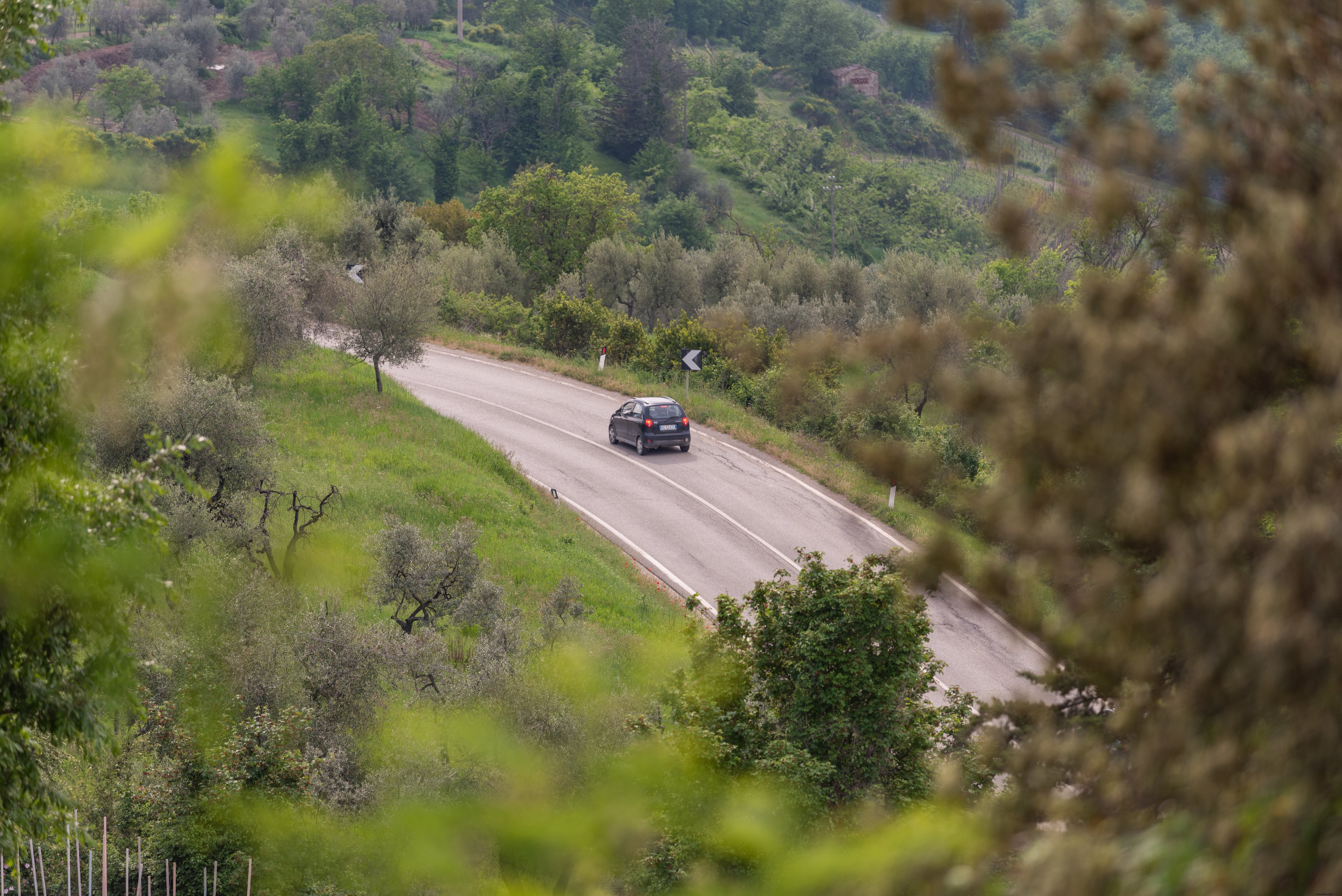 Un coche da la vuelta a una curva en una carretera en una colina Foto