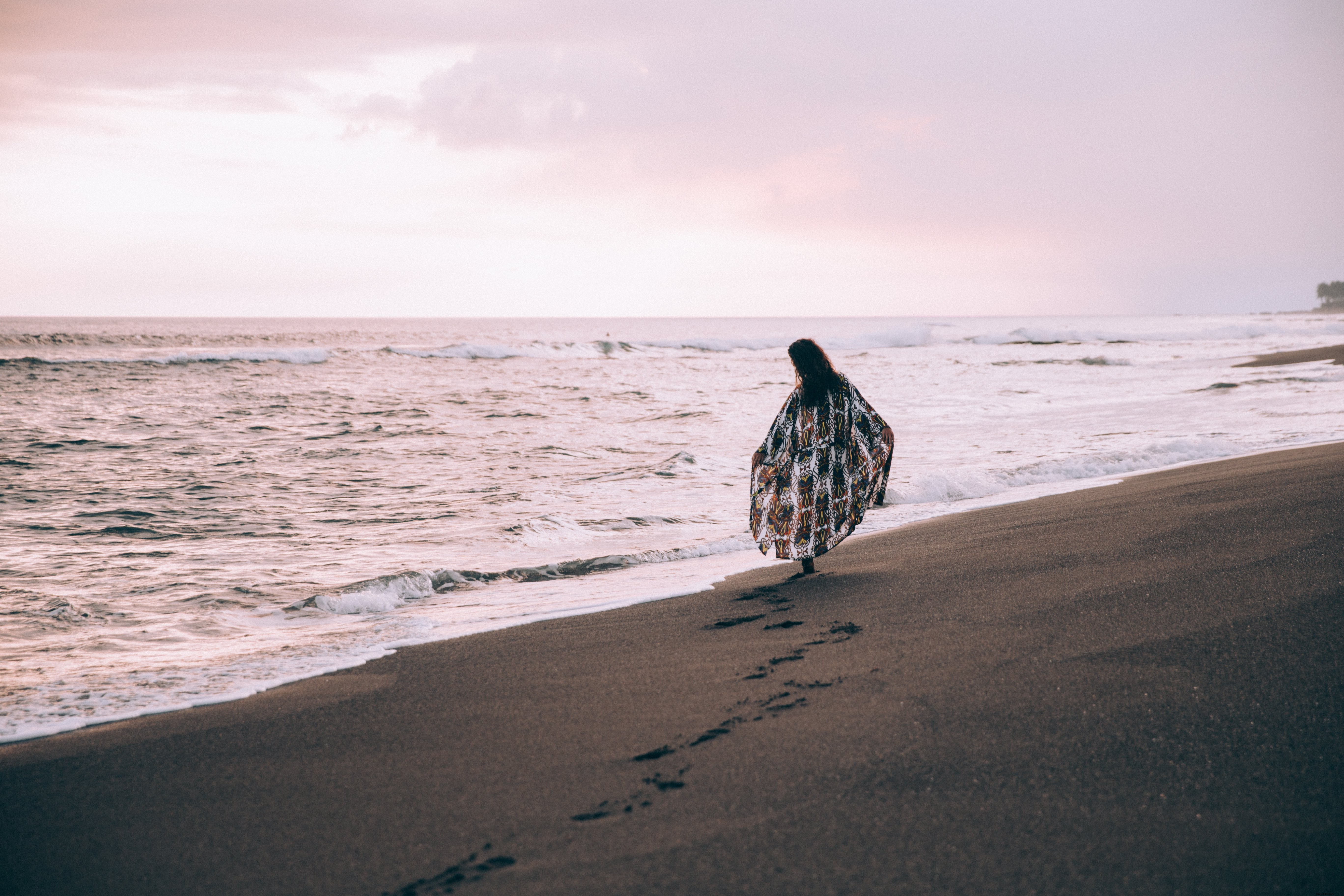 Une femme marche le long de la plage en laissant des traces de pas dans le sable Photo