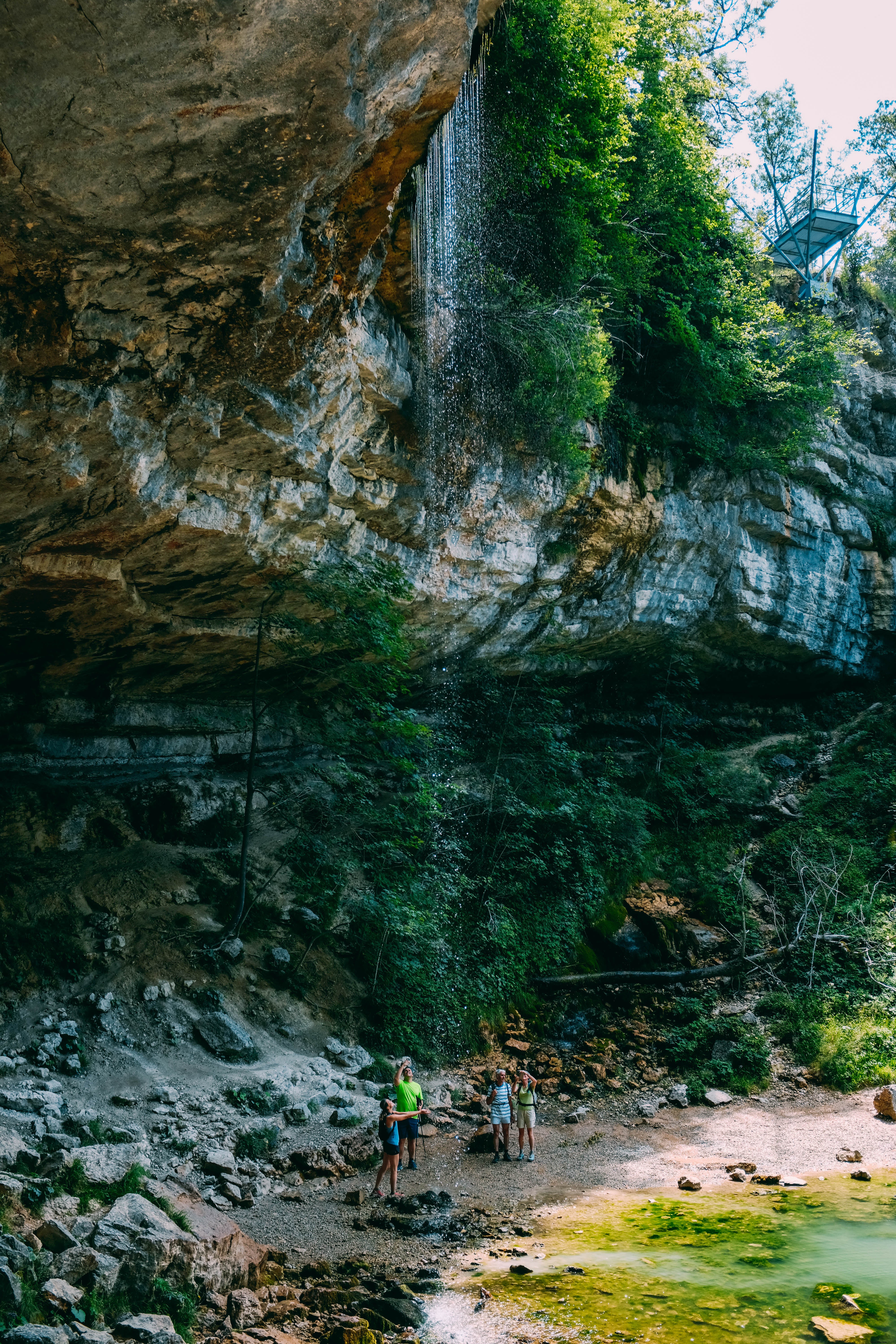 Pejalan Kaki Di Bawah Singkapan Berbatu Dan Foto Air Terjun Kecil