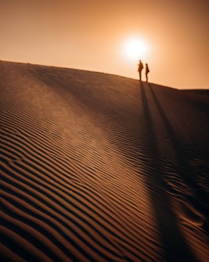 Sagome di persone in cima a una duna di sabbia foto