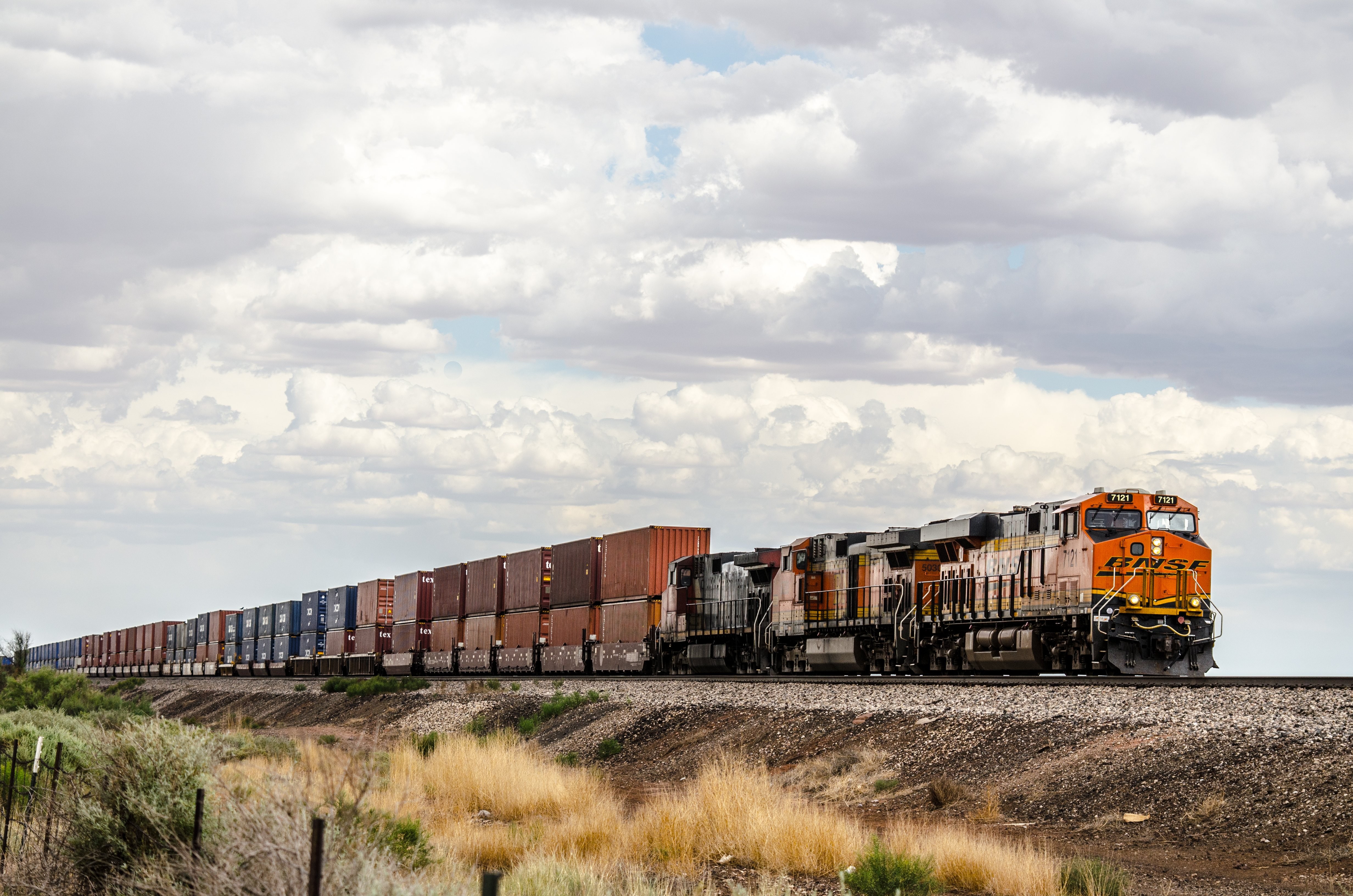 Um trem de carga transporta contêineres através da foto das planícies
