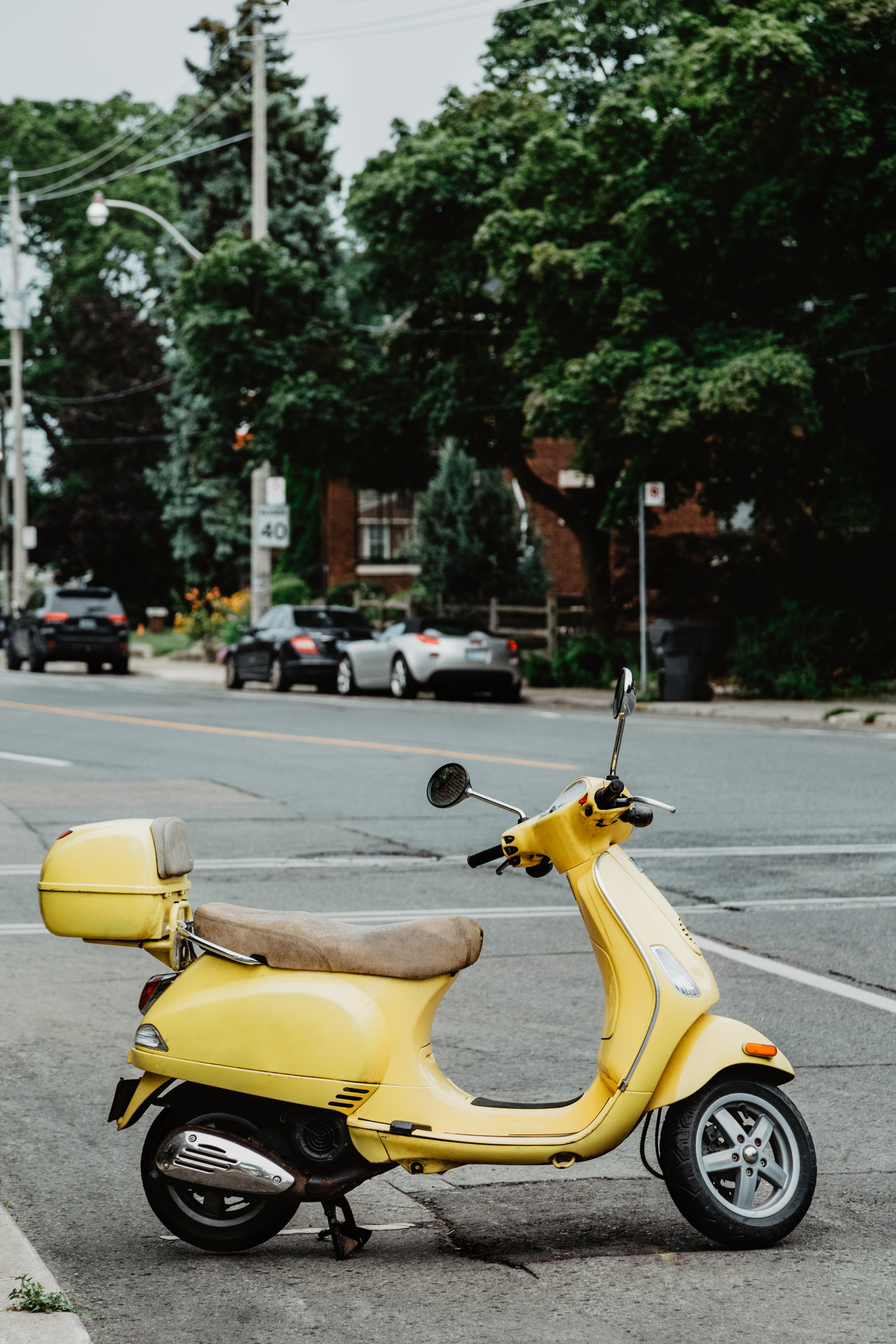 Um ciclomotor amarelo verão italiano estacionado em uma foto de rua