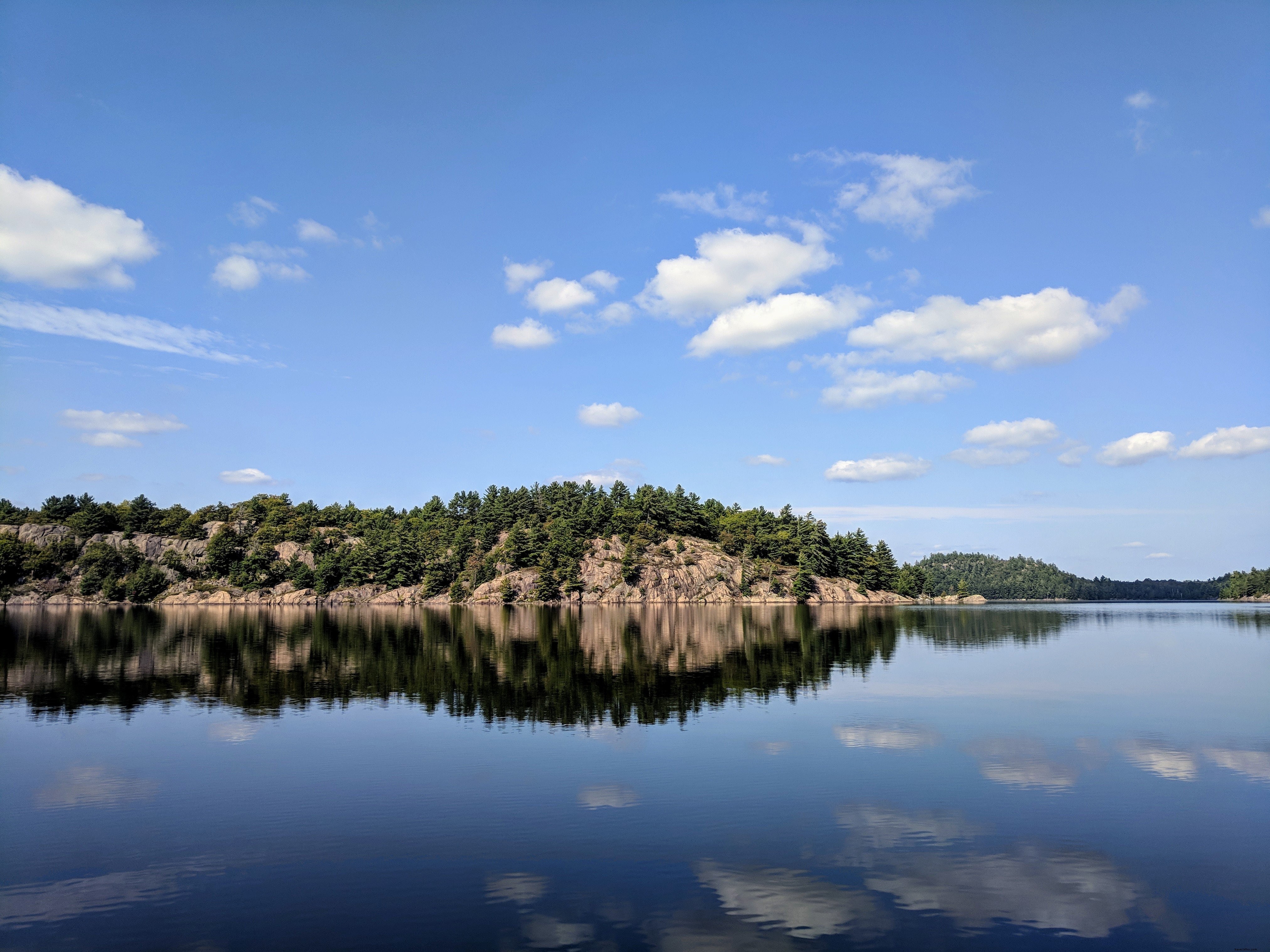 Foto do reflexo de rochas e árvores no lago