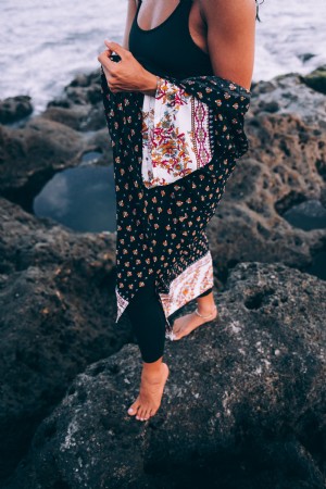 Una donna abbronzata con uno scialle fantasia posa sulla spiaggia foto