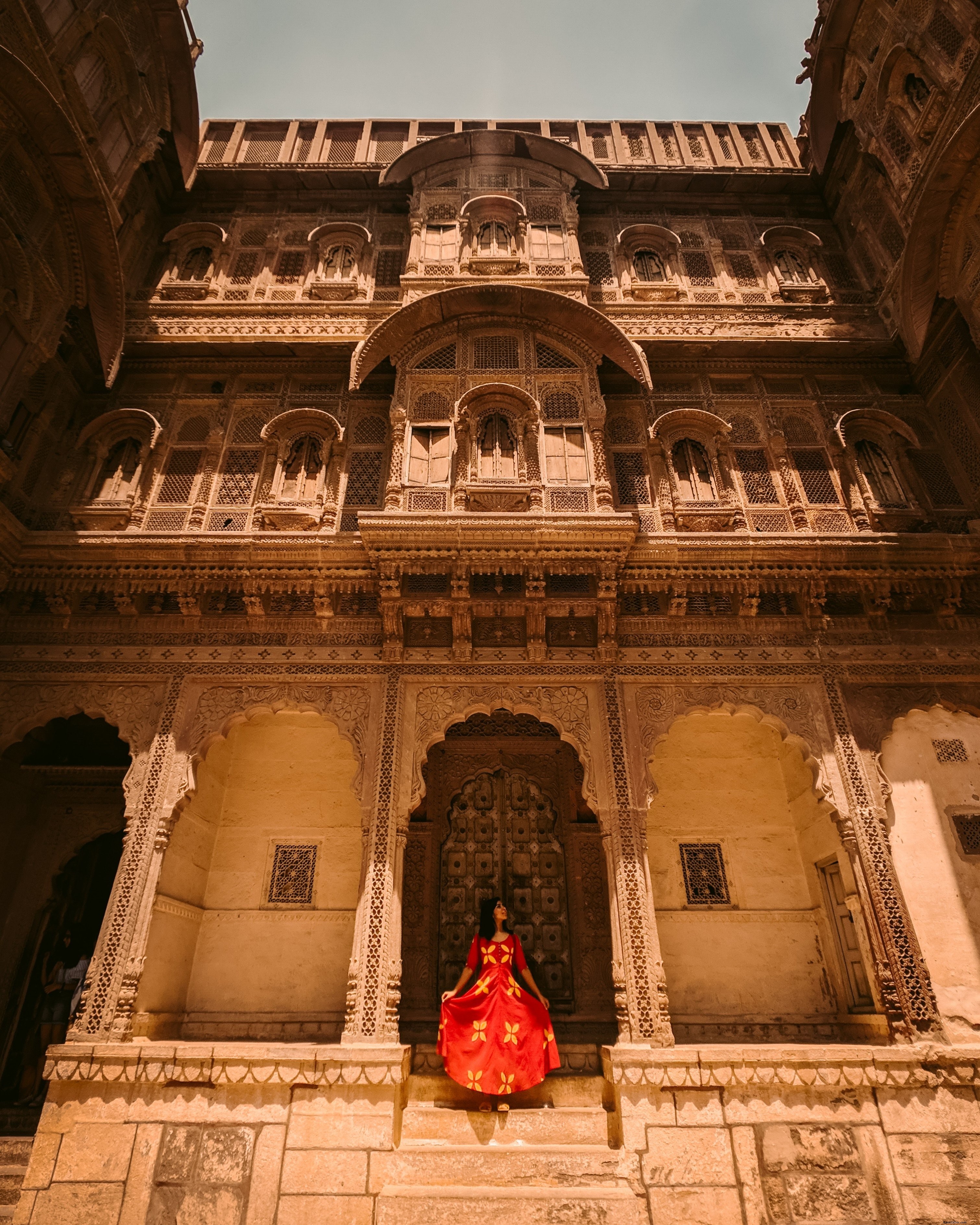 Mujer vestida de rojo posa delante de la foto del templo