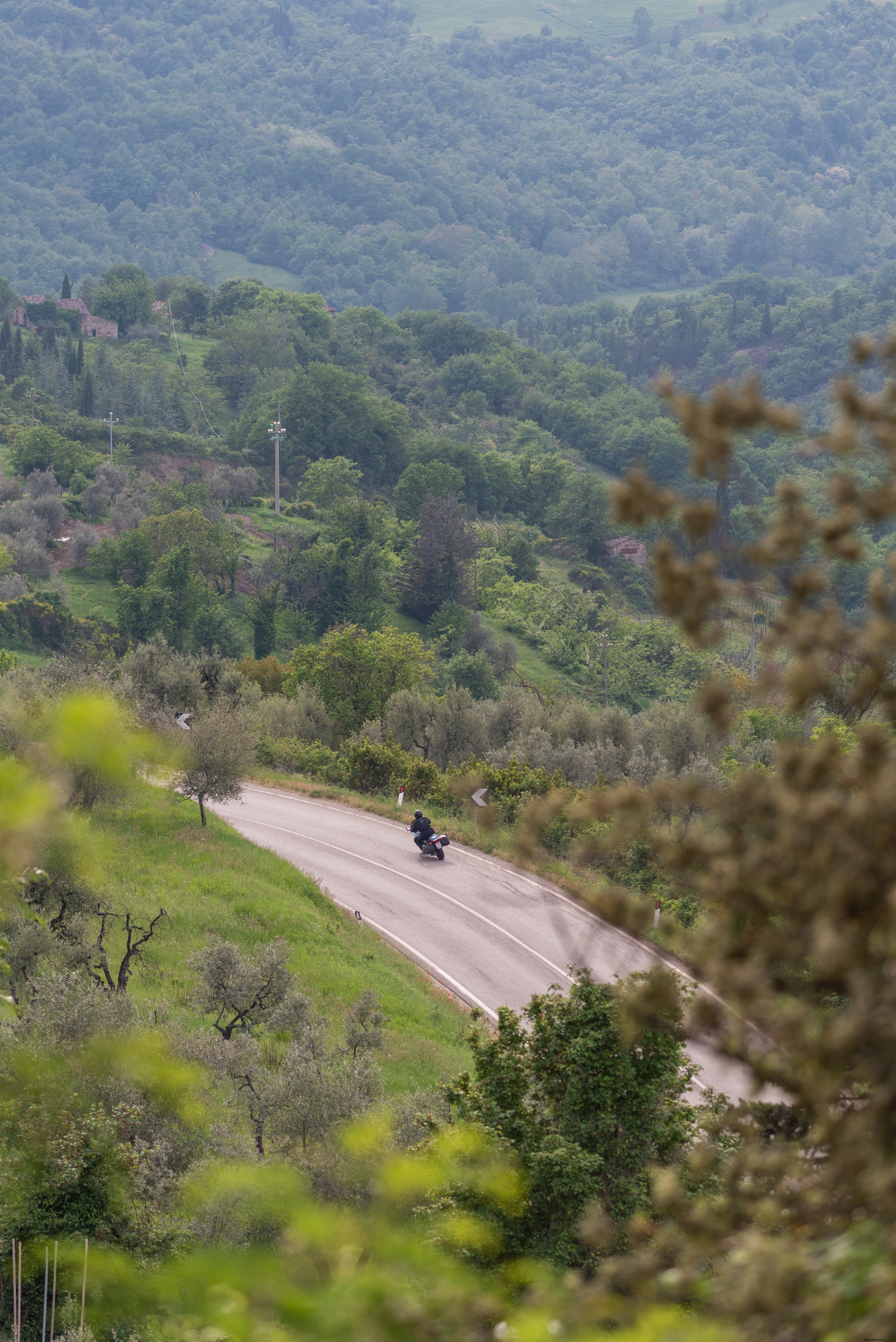 Una motocicleta toma una curva en una carretera alrededor de una colina Foto