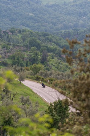 Una moto fa una curva su un autostrada intorno a una collina Foto