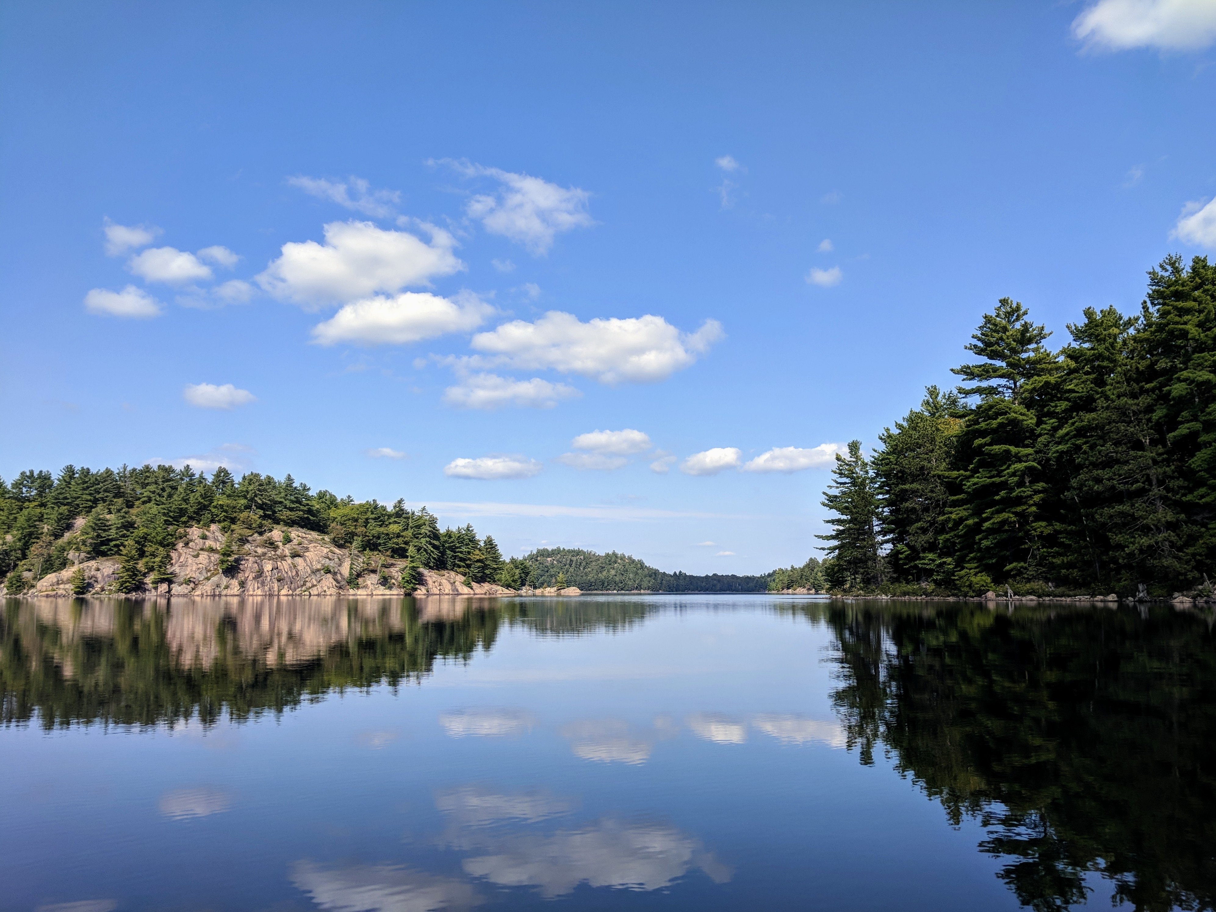 Rochas e árvores refletidas no lago calmo. Foto