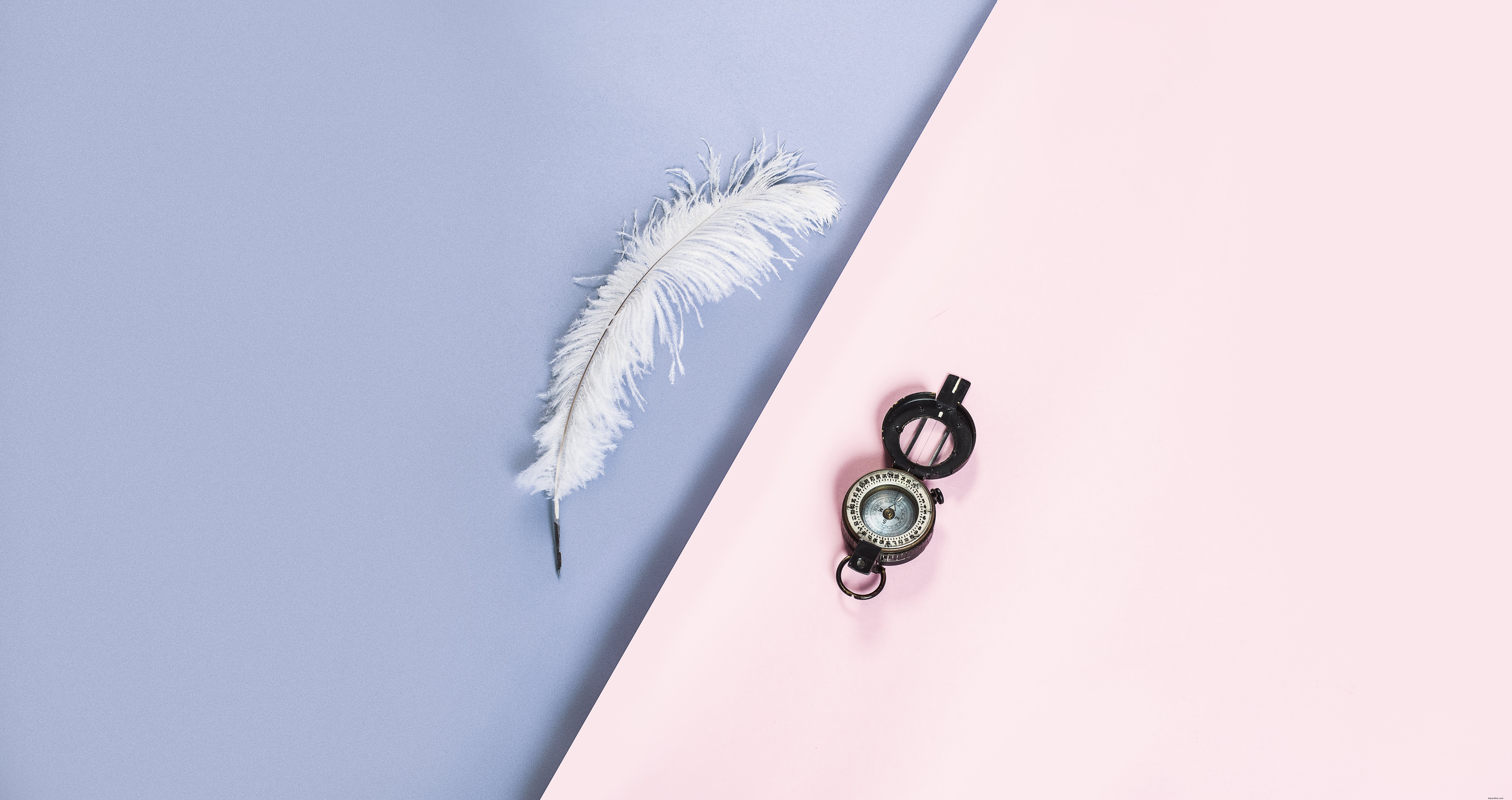 Una pluma blanca y una brújula en una foto rosa y morada