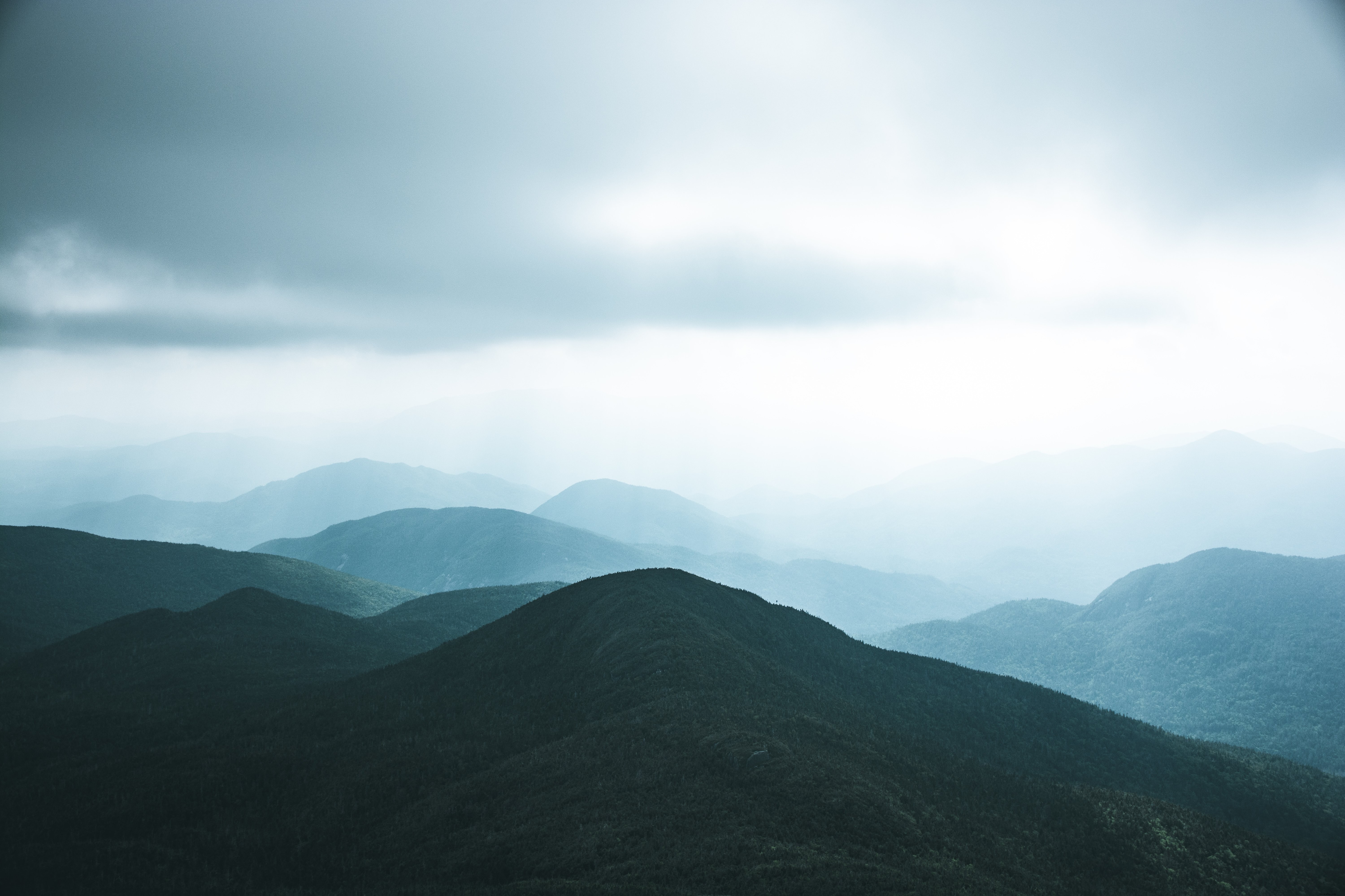 Foto de uma colina verde escura contra o céu esfumaçado