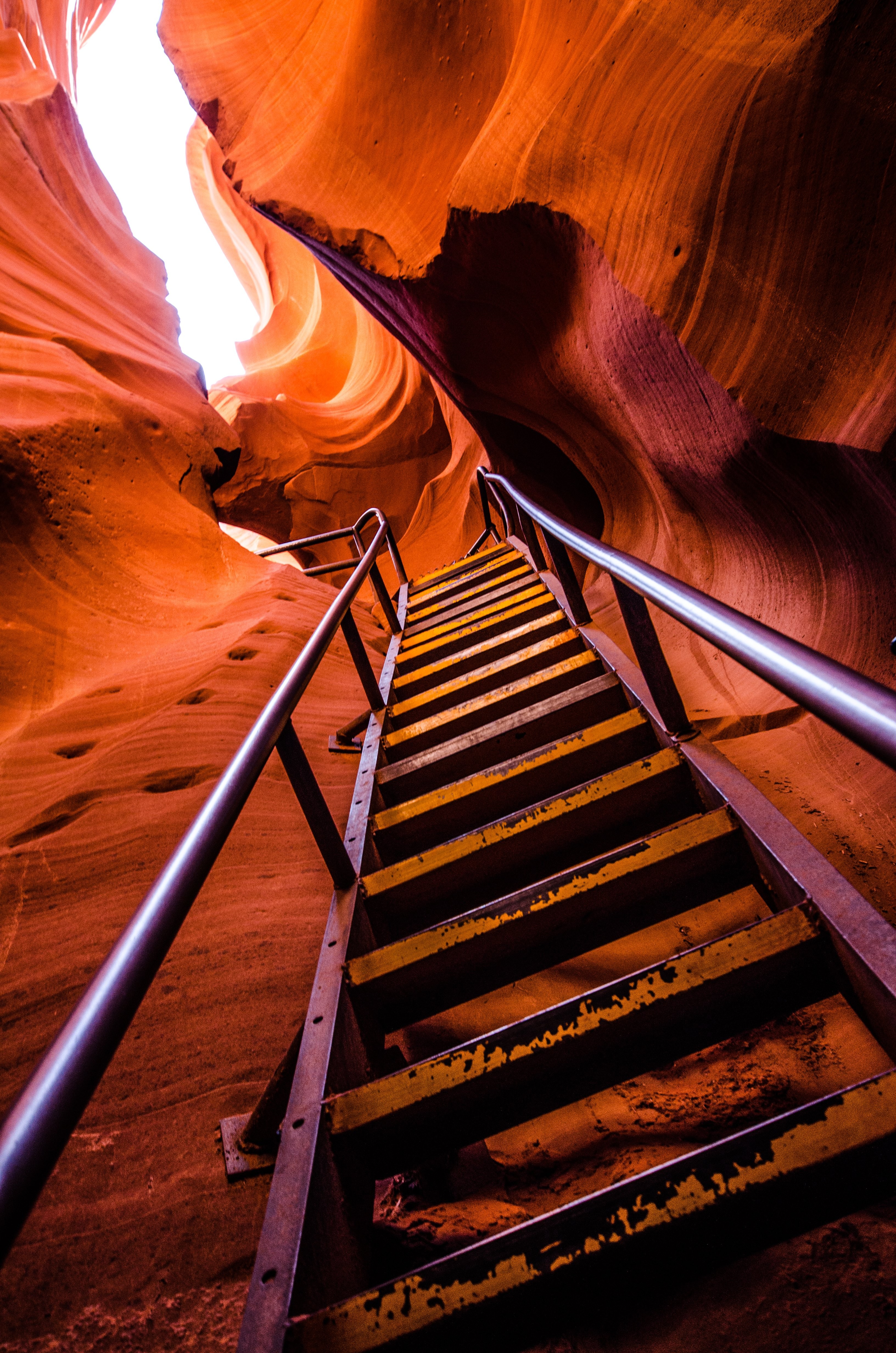 Una escalera escala los lados empinados de una cueva de arenisca roja Foto