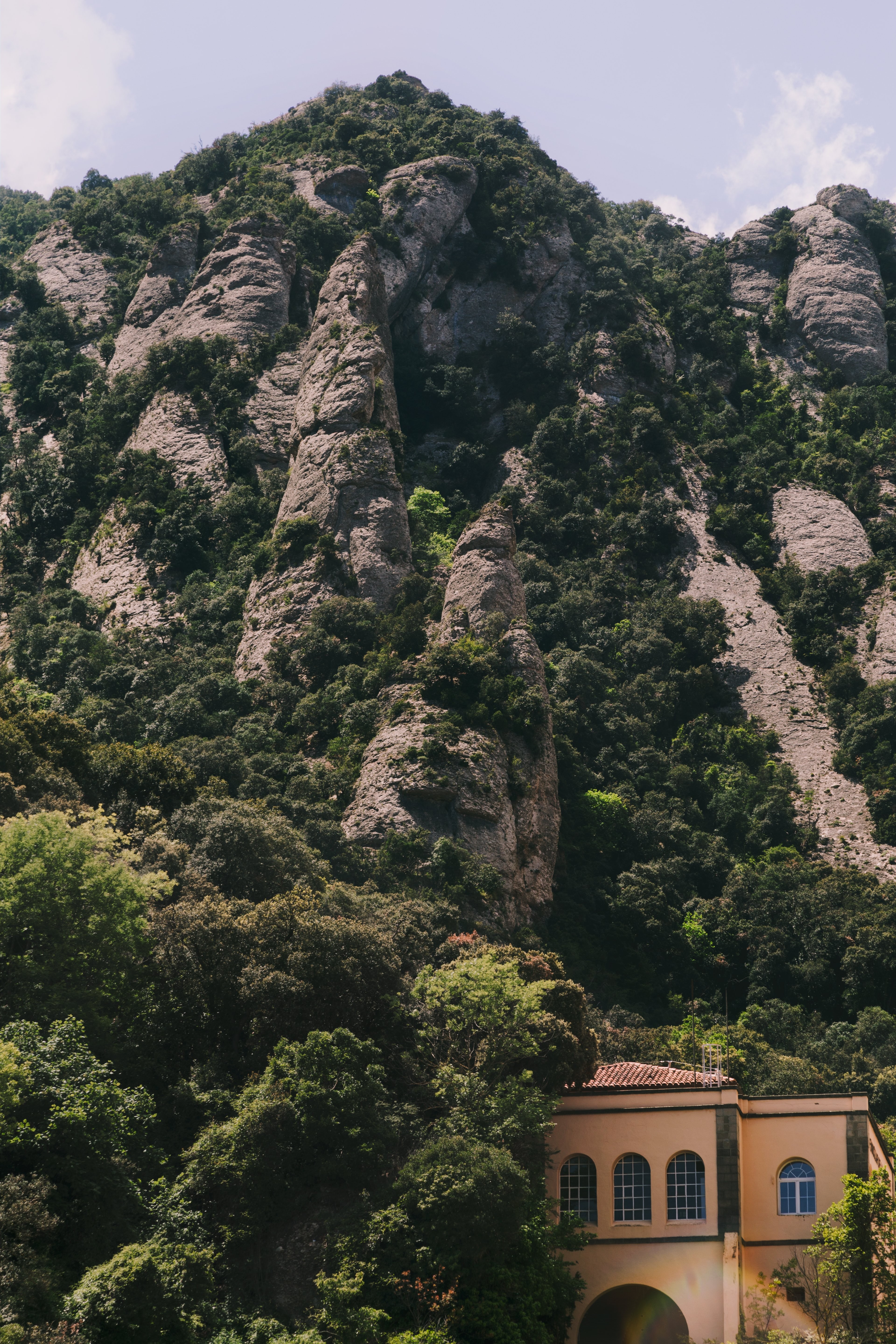 Una piccola villa alla base di una verde collina rocciosa Photo