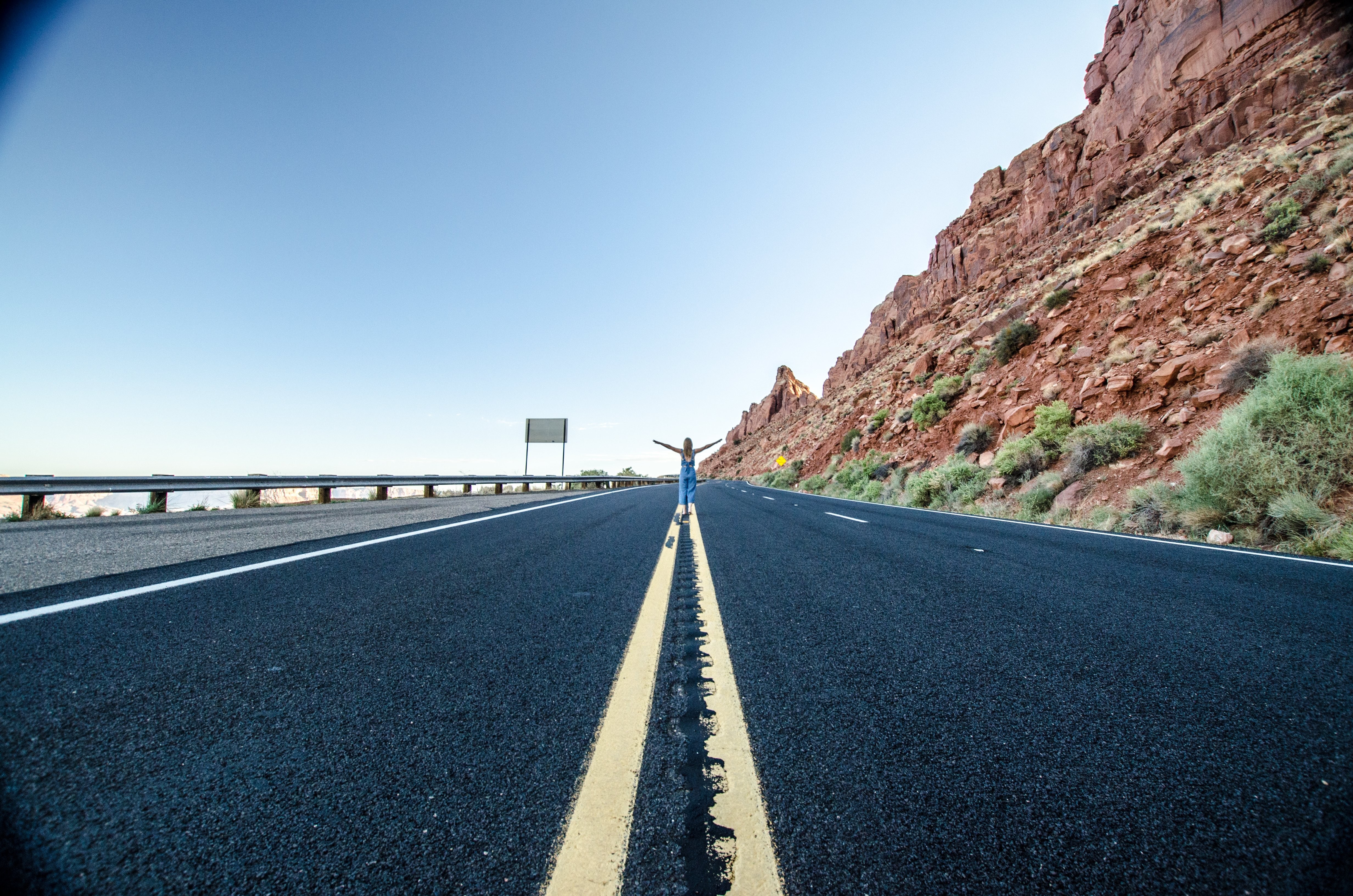 Foto de uma mulher parada no meio de uma rodovia no deserto