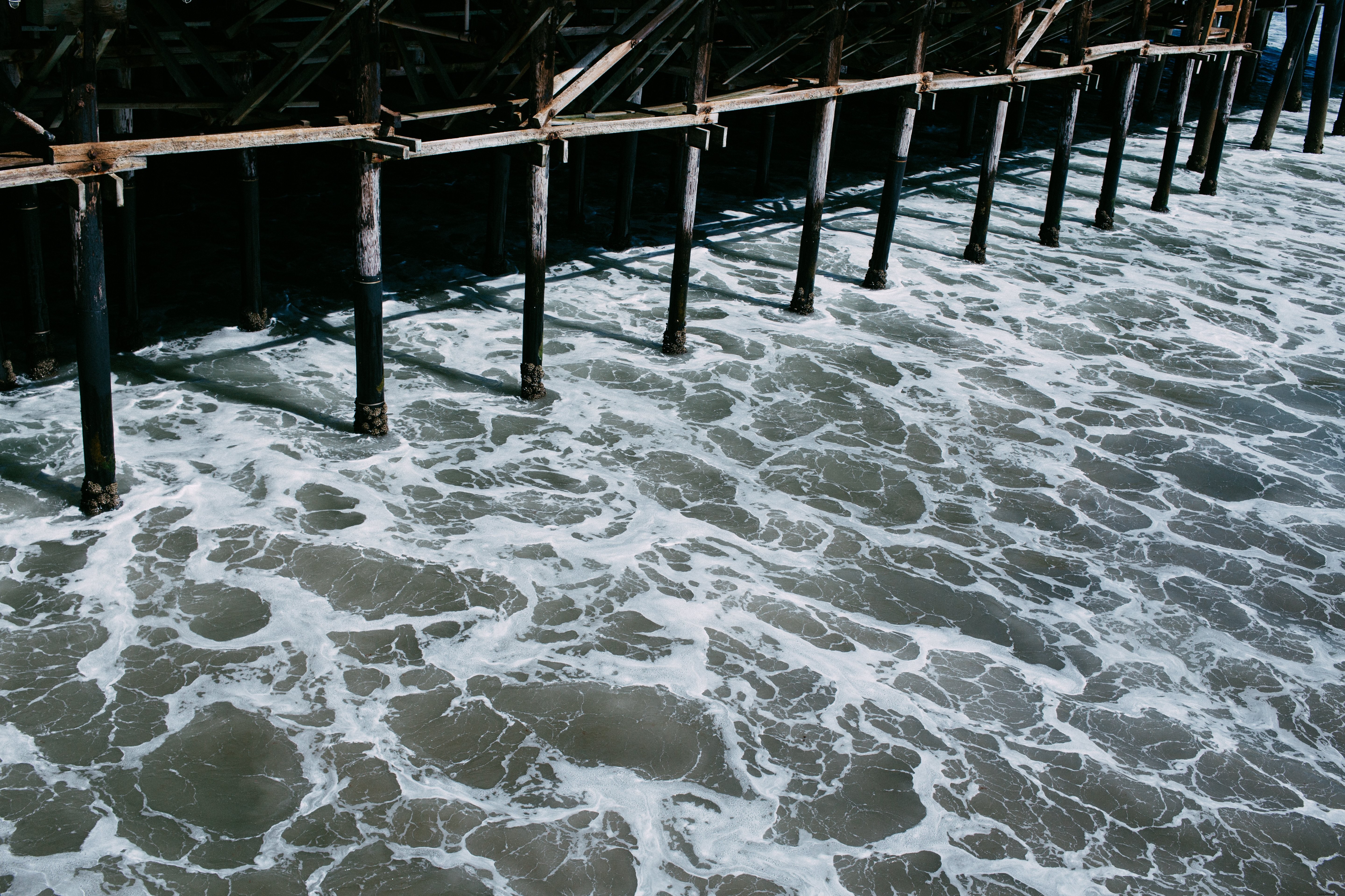 Agua que fluye debajo de la foto del muelle sombrío