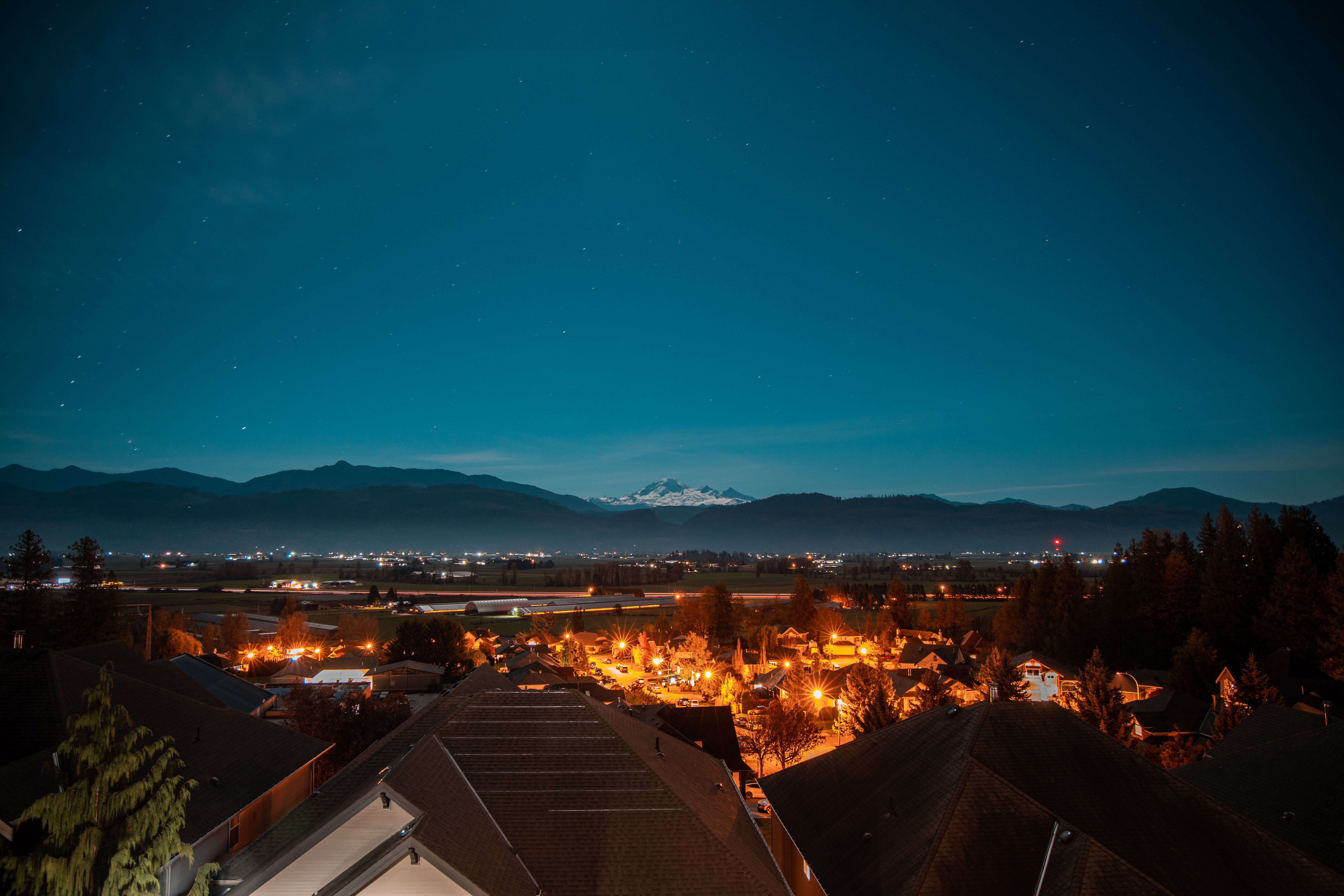 La ciudad mira hacia las montañas cubiertas de nieve y una foto de cielo estrellado