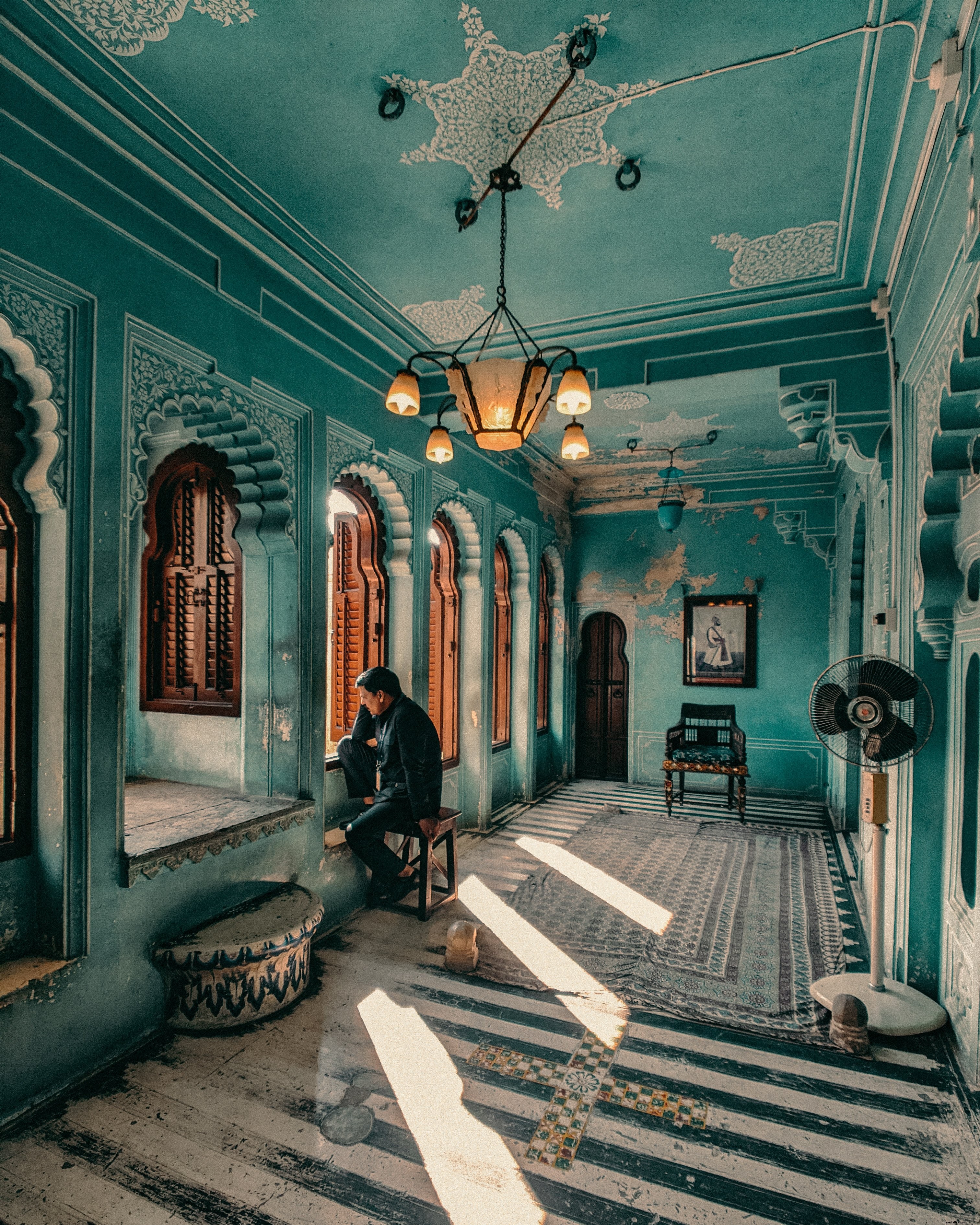 Homem sentado em um corredor azul ornamentado, foto