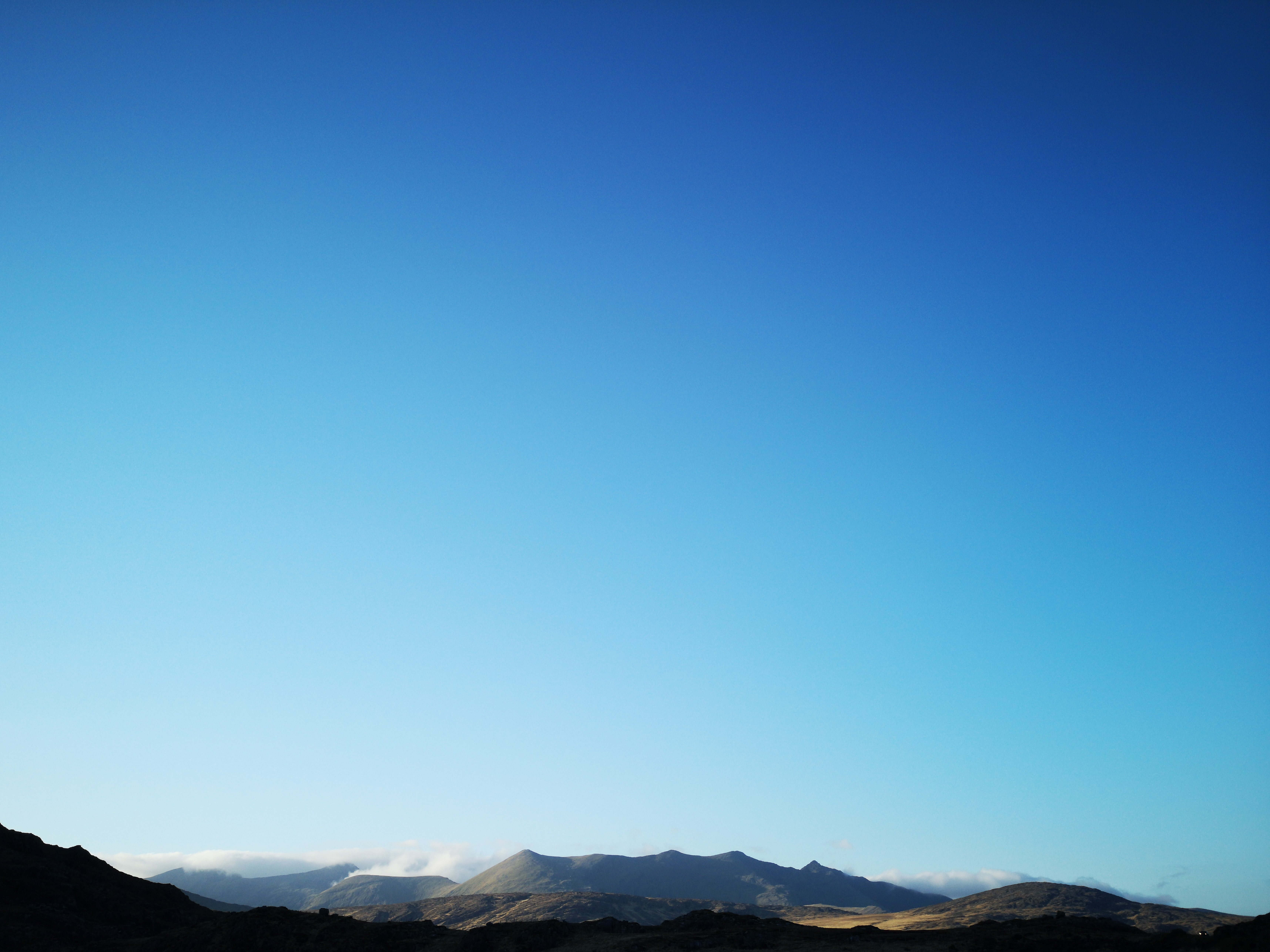 太陽に照らされた山々の上の青い空写真