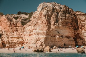 岩だらけの石灰岩の断崖が砂浜の写真に迫る