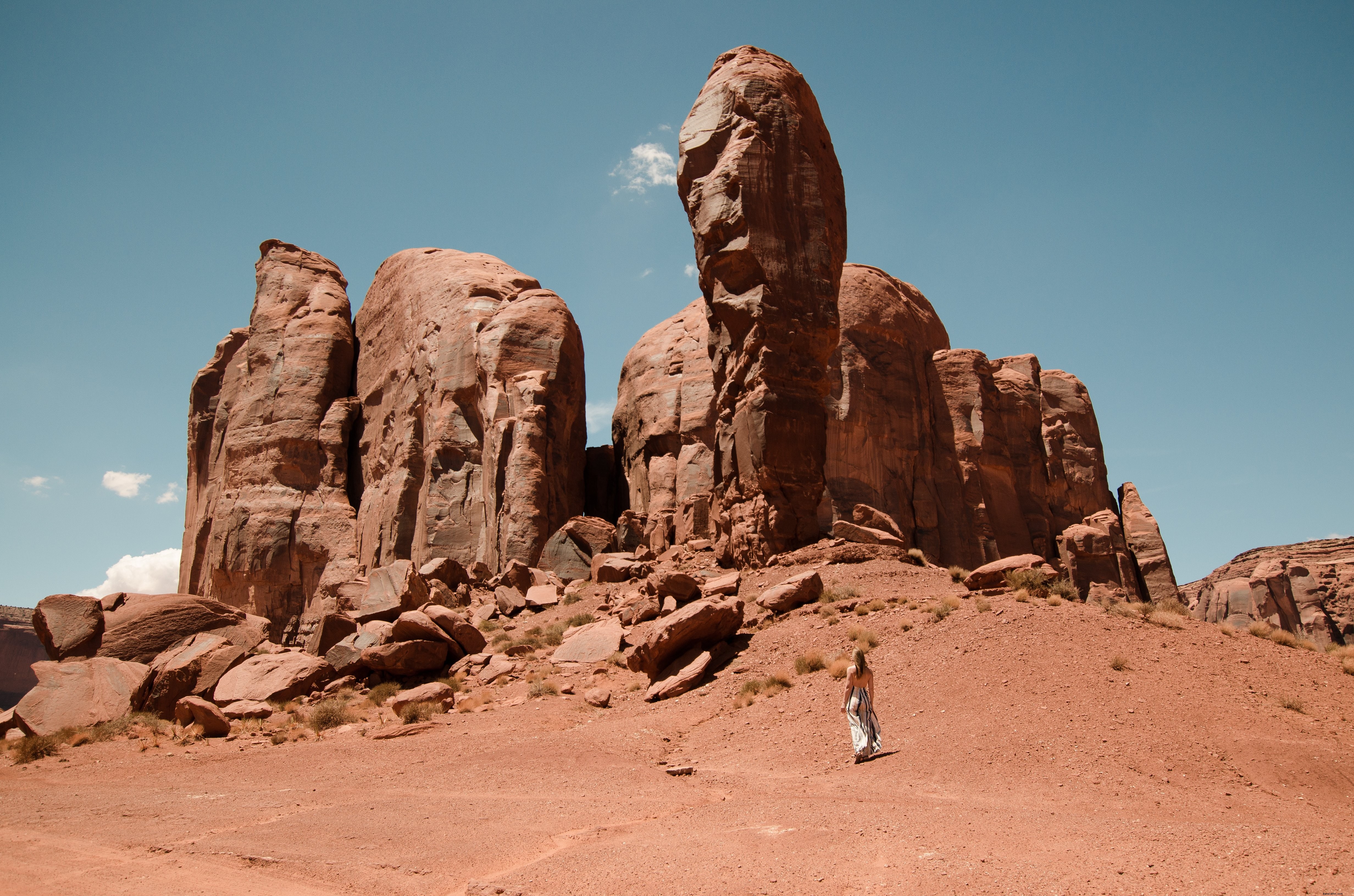 砂漠の山々のずんぐりした石の指を見上げる女性の写真