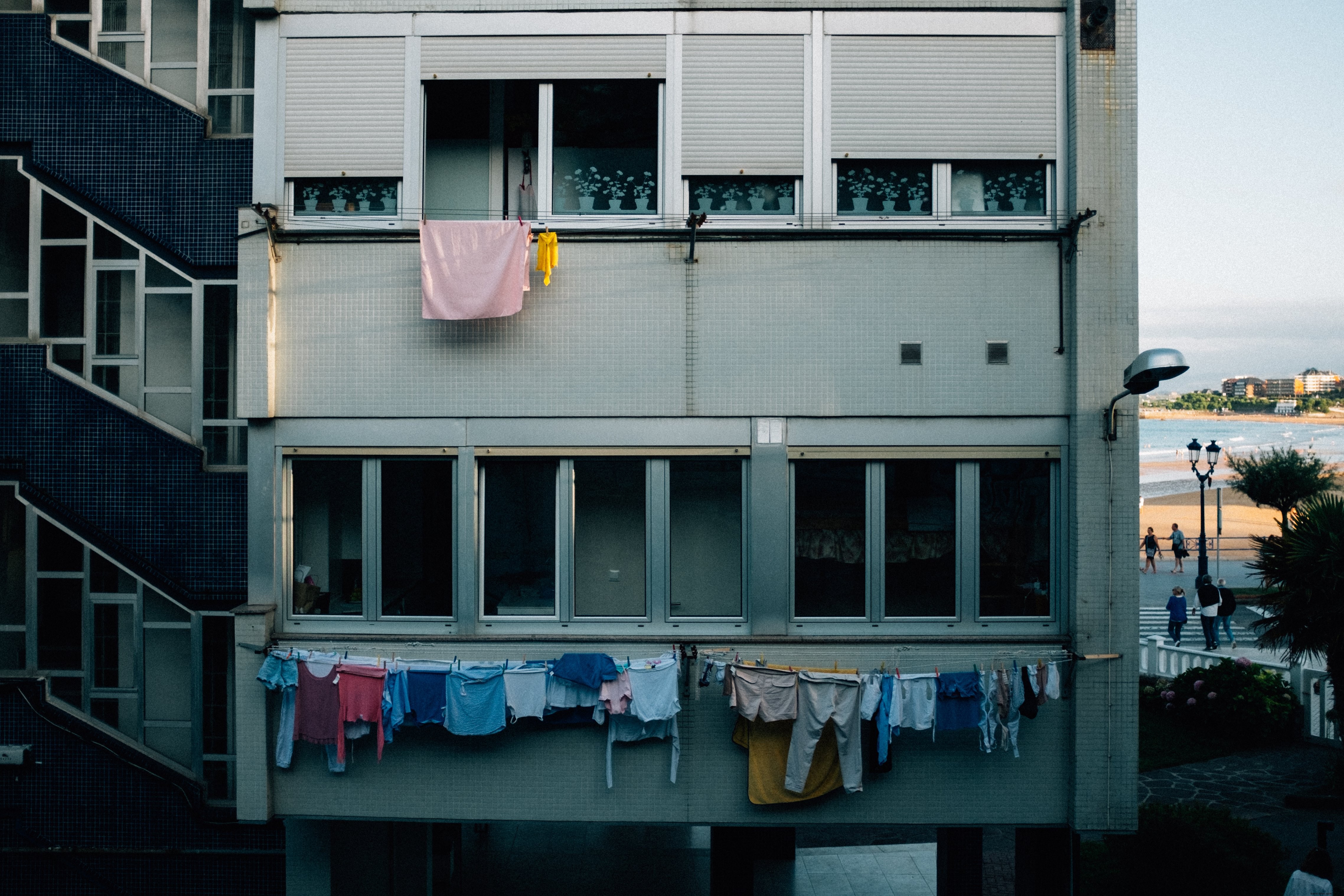 A face cinzenta de um bloco de apartamentos coberto por varais de roupas.