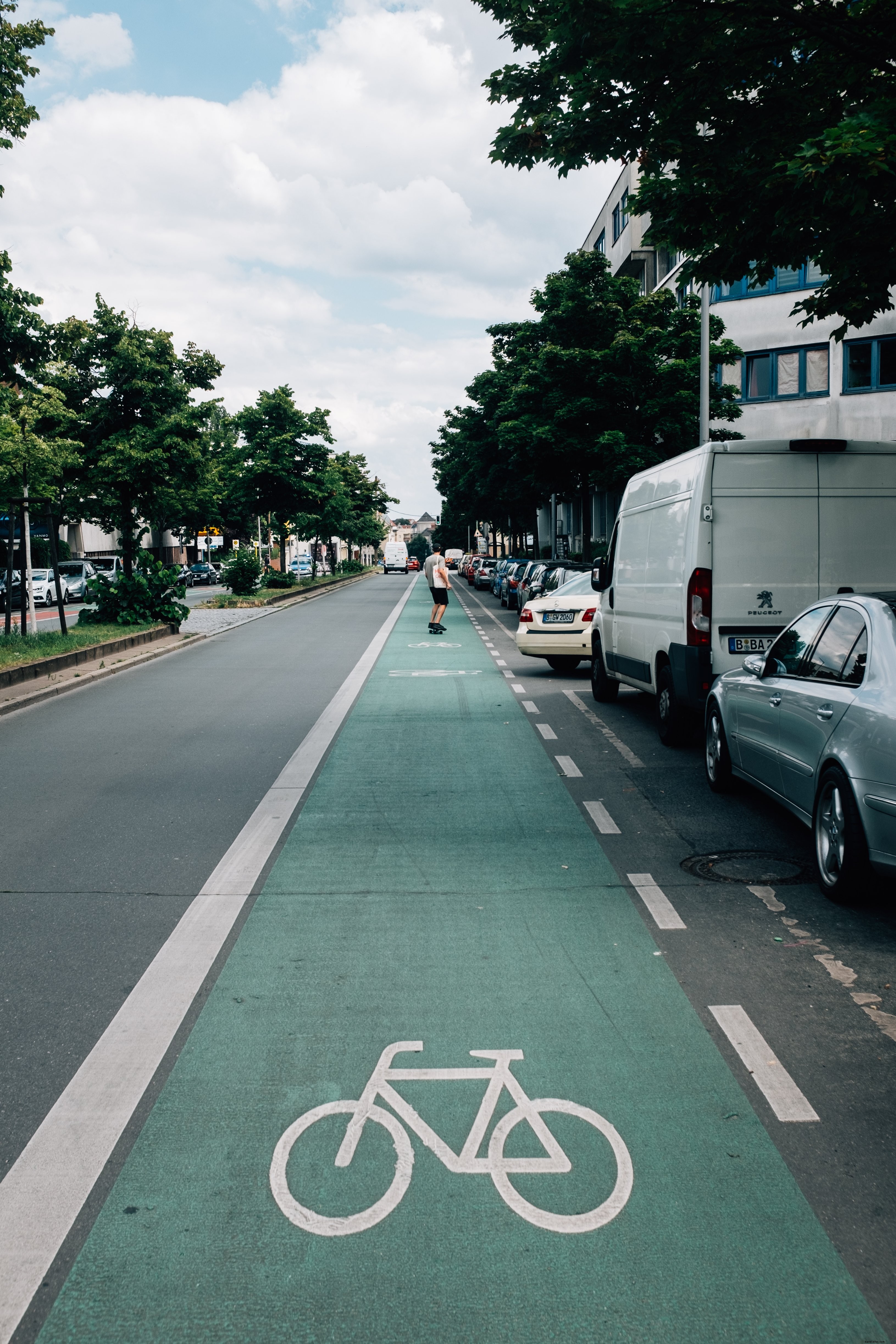 晴れた日に自転車専用車線を使用するスケートボーダーの写真