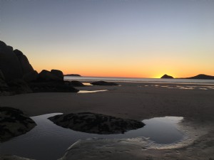 ビーチの水の水たまりは夕日の写真を反映しています