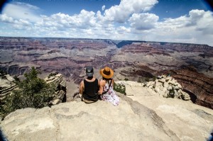 Una giovane donna e un uomo siedono con vista su un canyon foto