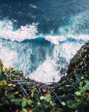 崖の写真のベースで青い波がクラッシュ