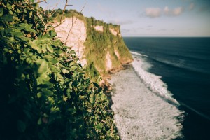 緑に覆われた崖が砕ける波に出会う写真