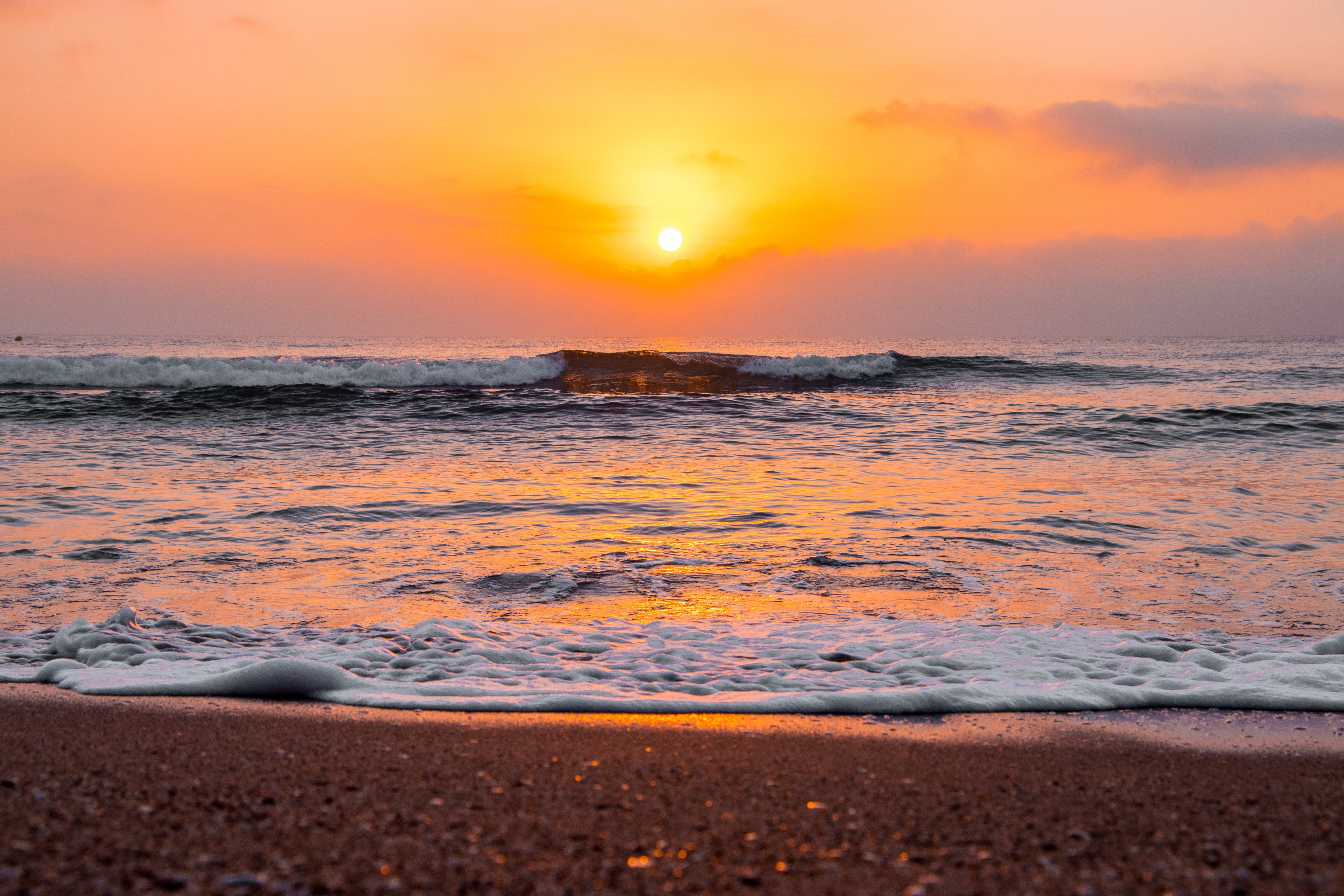 Amanecer sobre el océano ondulado en la playa de arena Foto