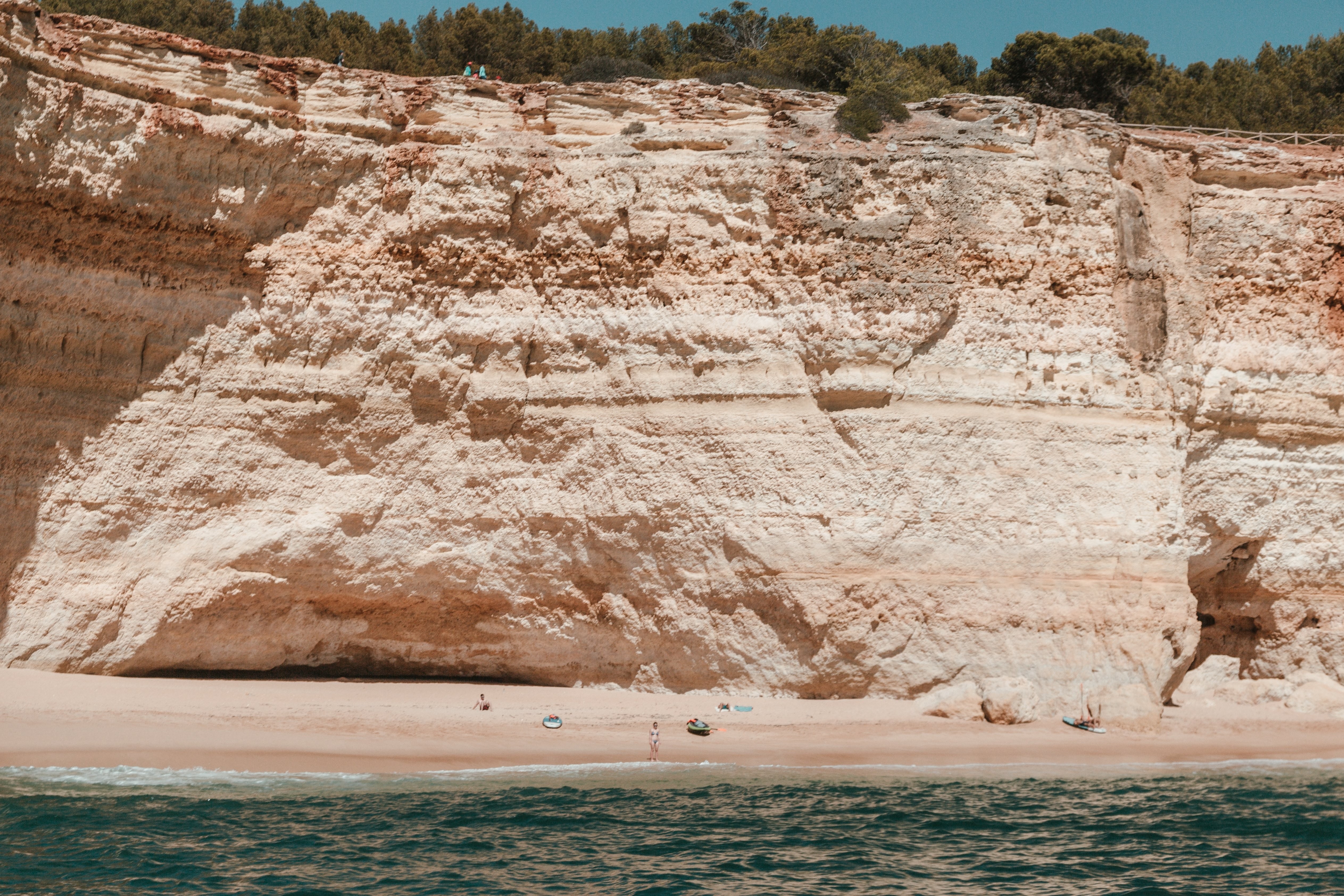 Kayakistas y surfistas en una playa de arena bajo acantilados de piedra caliza Foto