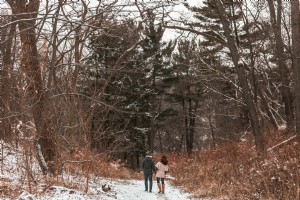 Sepasang kekasih Berjalan Melalui Foto Hutan yang Tertutup Salju