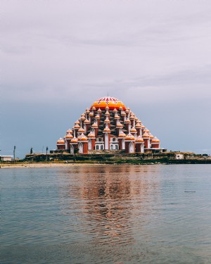 Foto de templo à beira-mar se reflete na água