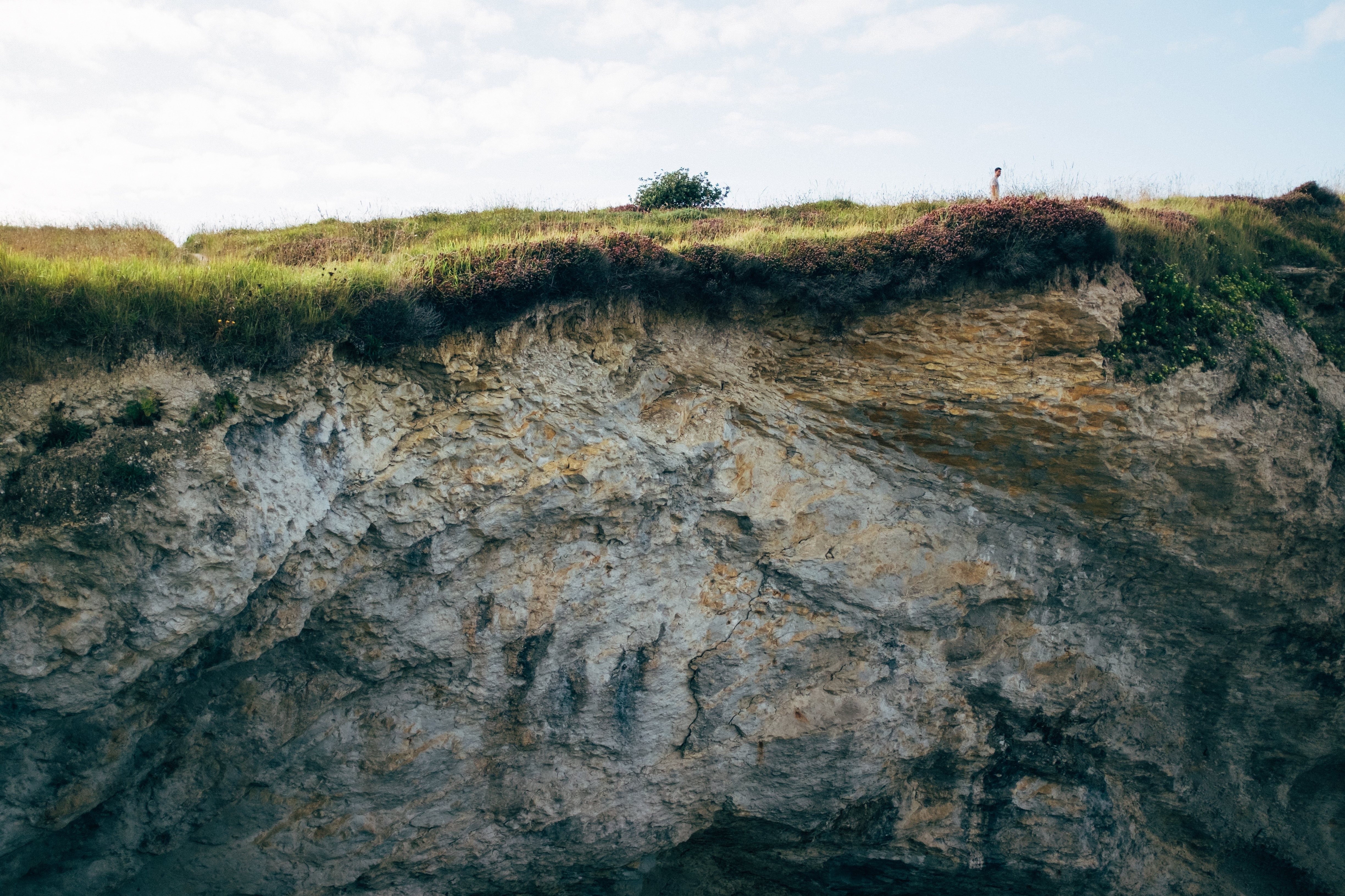 La petite figure d un homme marchant sur la colline au sommet d une falaise Photo