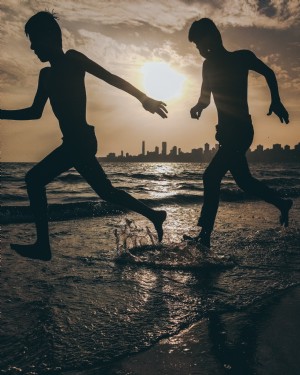 Silhouettes de deux personnes s éclaboussant sur la plage Photo