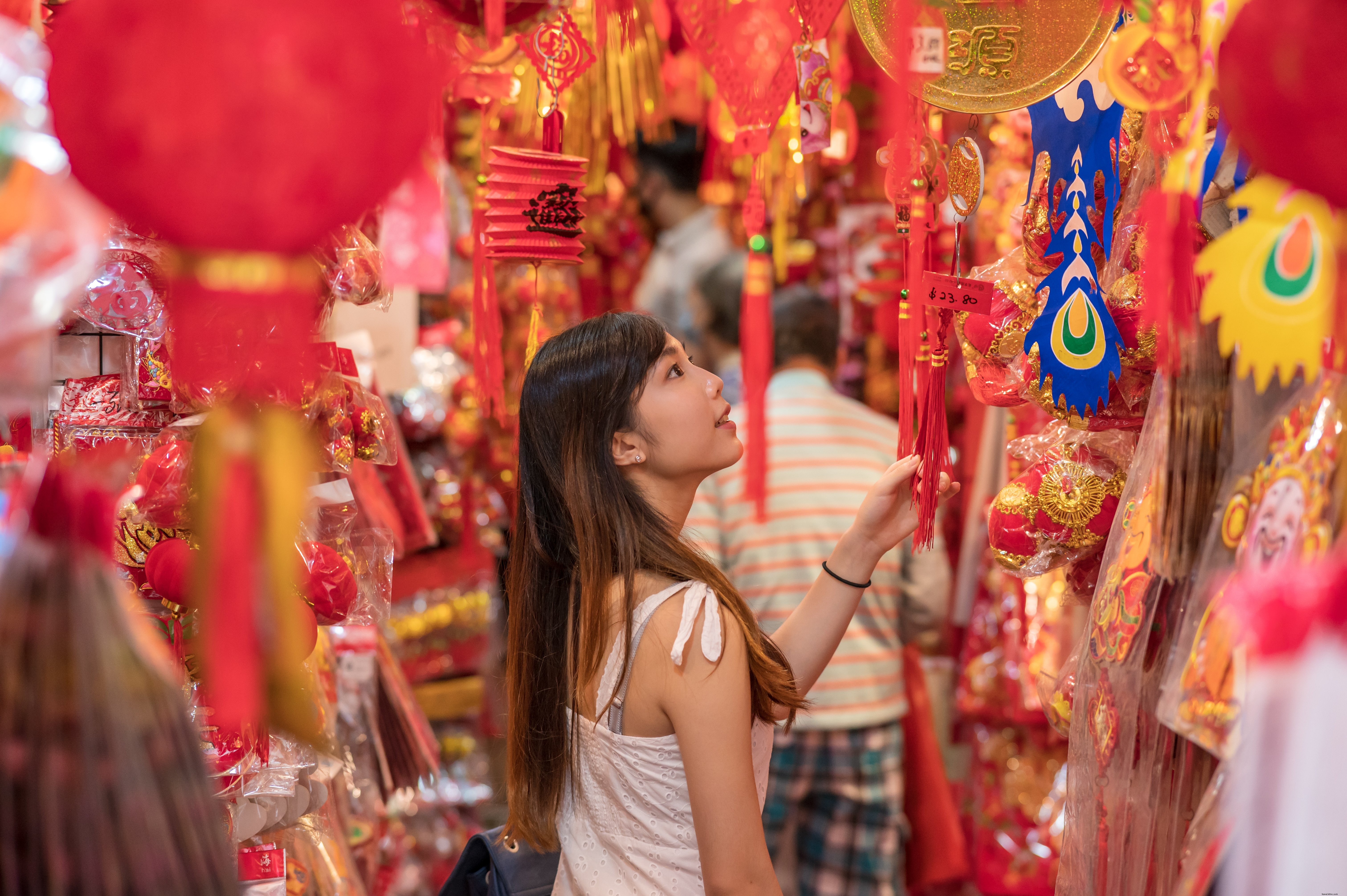 Persona en un mercado está rodeada de artículos rojos y dorados Foto 