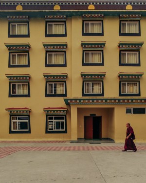 Foto de un monje budista paseando por un edificio amarillo 