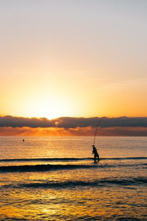 Pêcheur se tient dans l eau au lever du soleil Photo 