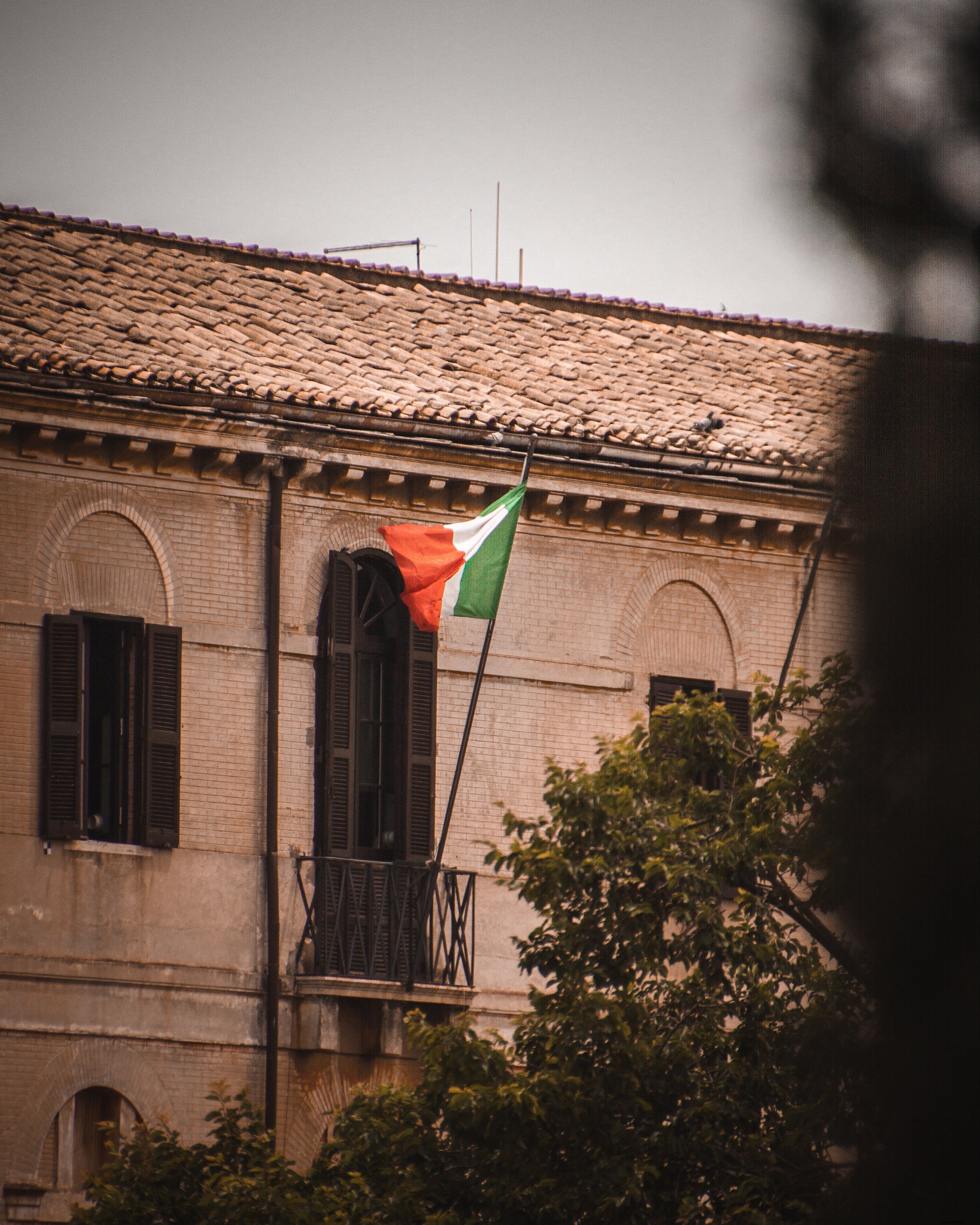Una bandera italiana ondea desde un balcón Foto 