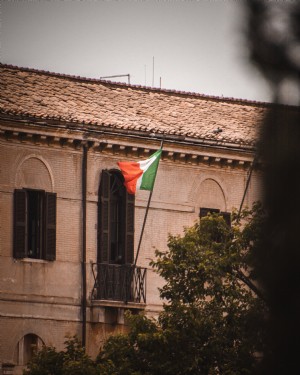 Una bandera italiana ondea desde un balcón Foto 