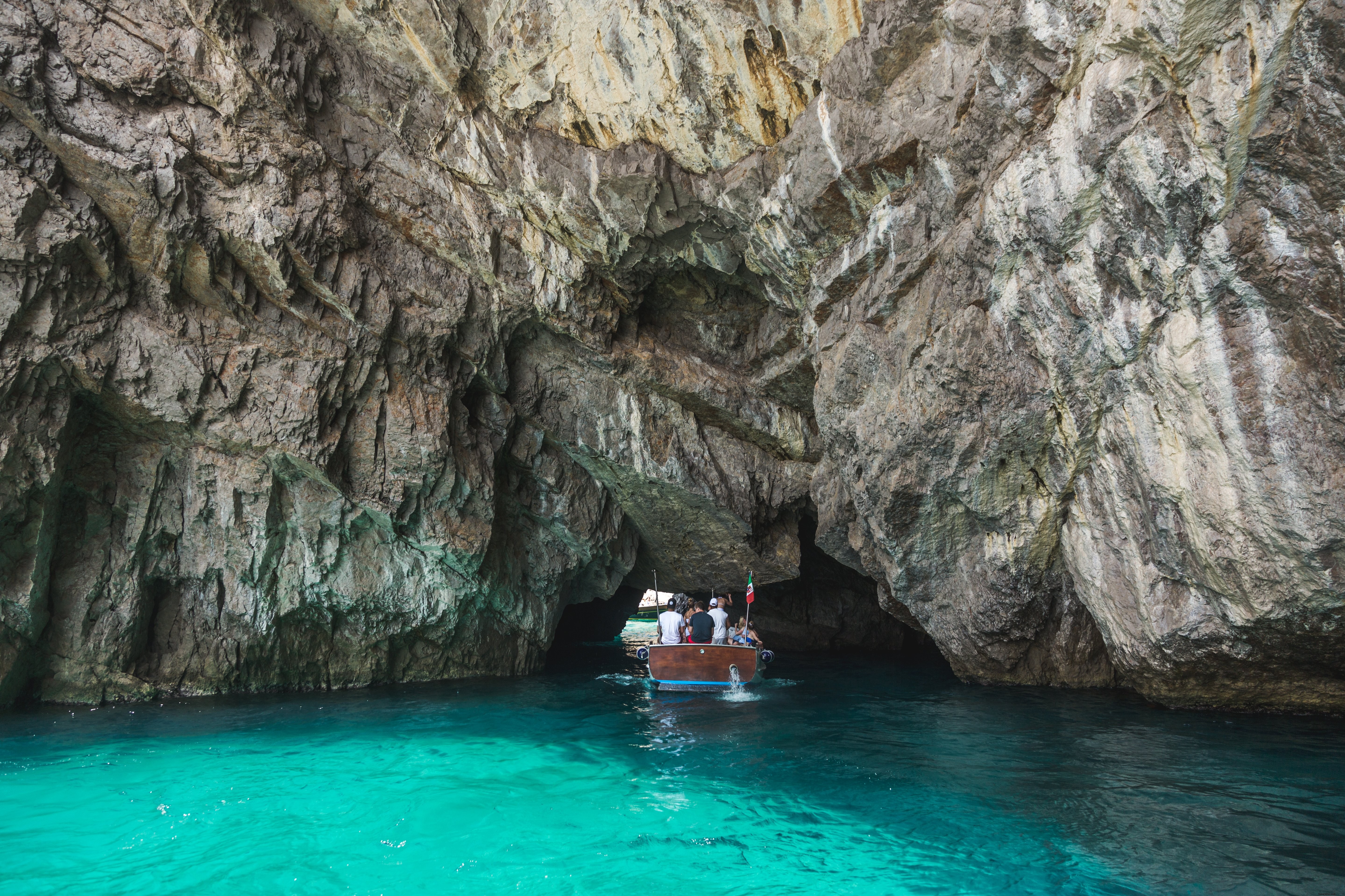 Foto de barco pequeño navegando bajo las rocas 