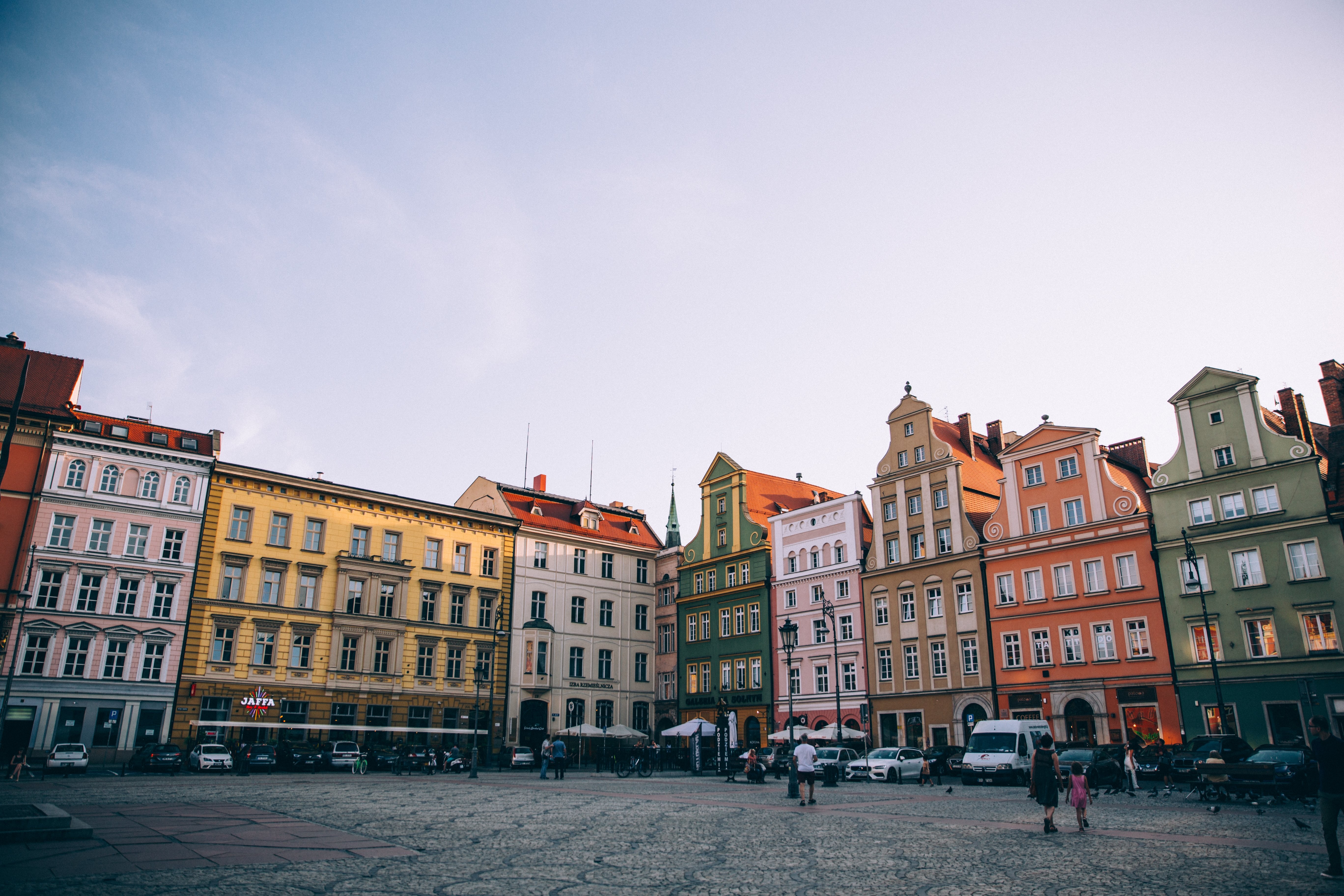 Pôr do sol em uma praça da cidade europeia repleta de edifícios coloridos. 