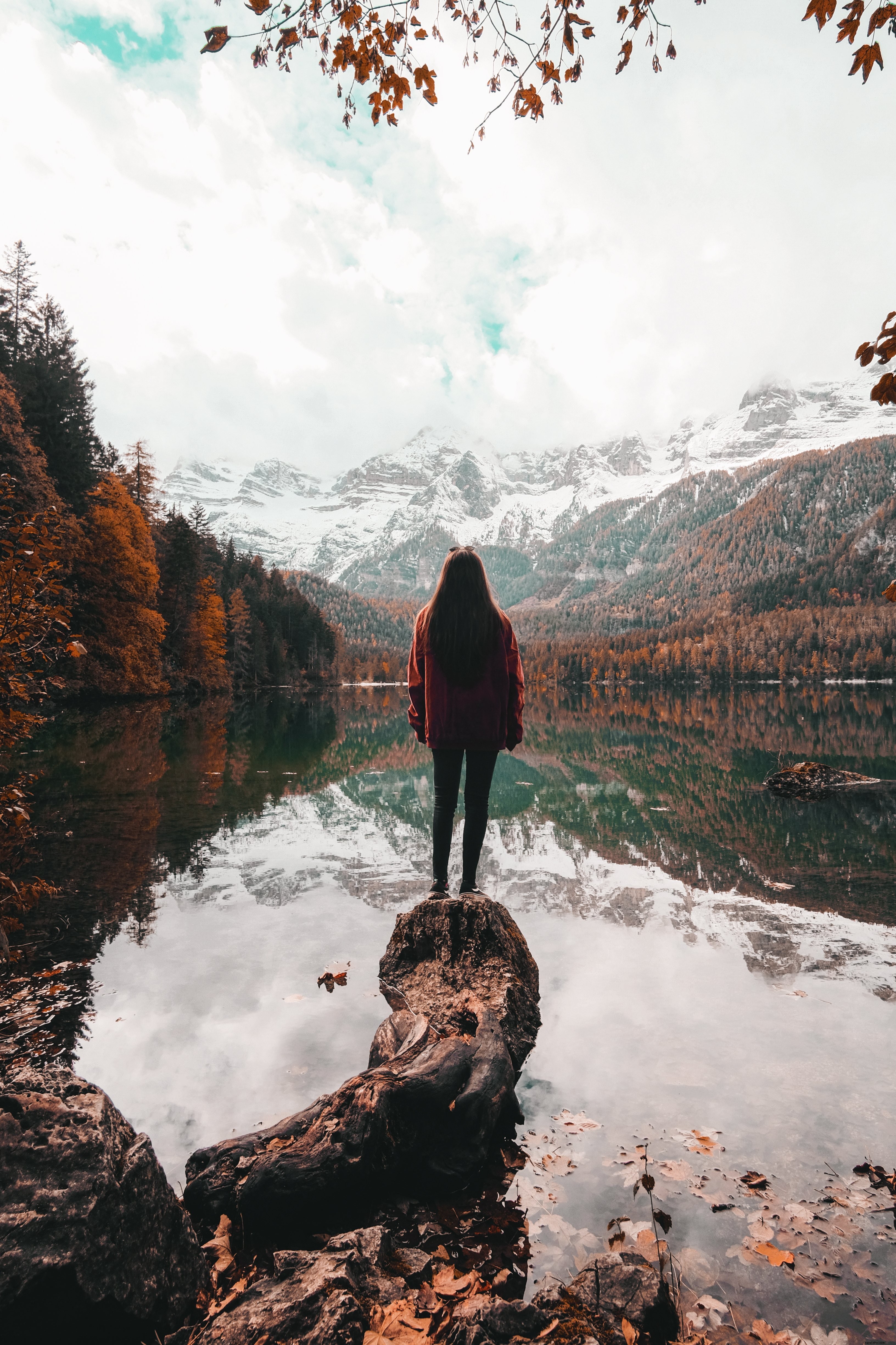 Persona mira hacia un día de otoño junto a un lago Foto 